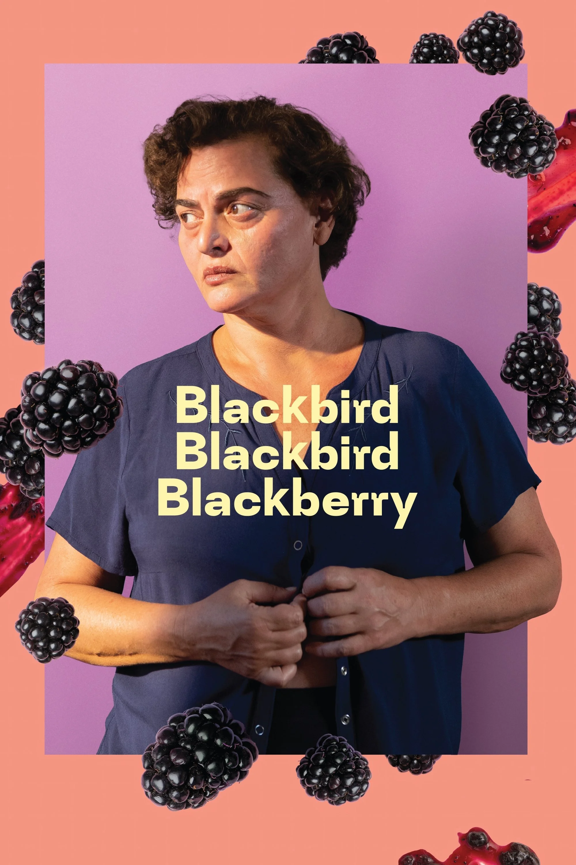 A woman with short curly hair and light makeup stands against a light purple background, wearing a dark blue shirt. She looks to her left with a serious expression, holding her hands together in front of her. The image is overlaid with the repeated text "Blackbird Blackberry" and surrounded by blackberries and a splash of raspberry juice on a peach-colored background.