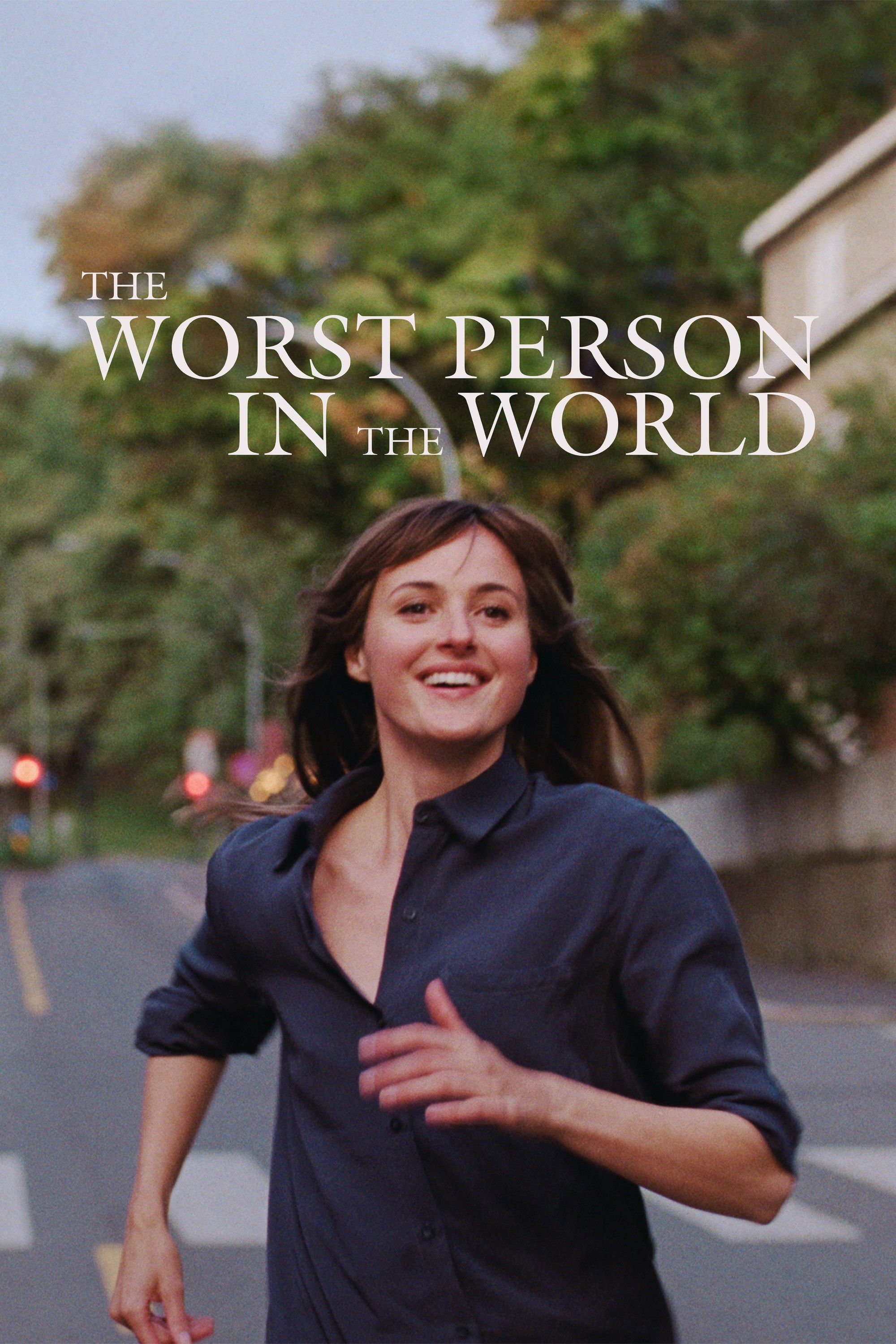 A woman with short brown hair running outdoors in a park with trees in the background, and a building partially visible on the right side of the image.
