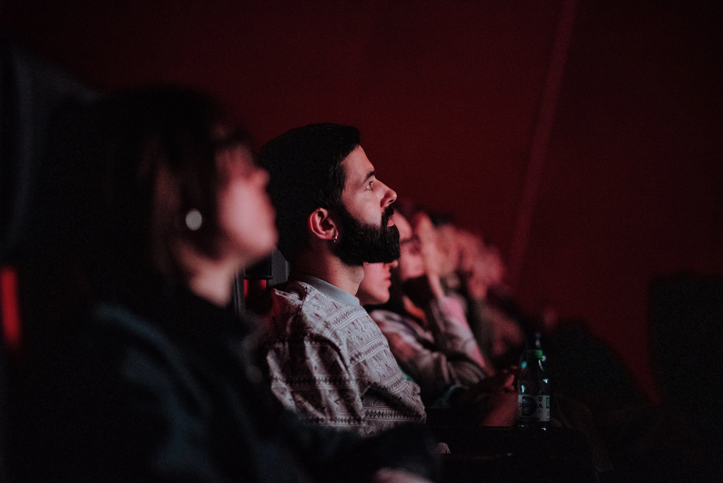 People sitting in a dark theater watching a movie or presentation.