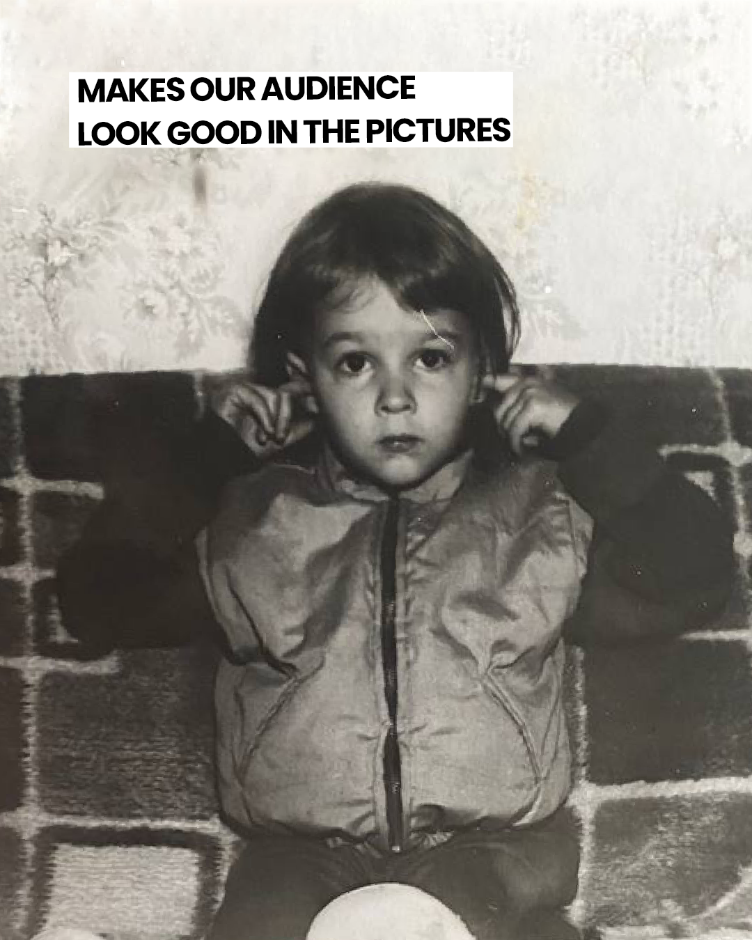 Black and white photo of a young child with short hair, wearing a jacket, sitting on a patterned rug with a ball in front. The child is covering their ears with their hands. Text overlay in the top left corner reads: "MAKES OUR AUDIENCE LOOK GOOD IN THE PICTURES."