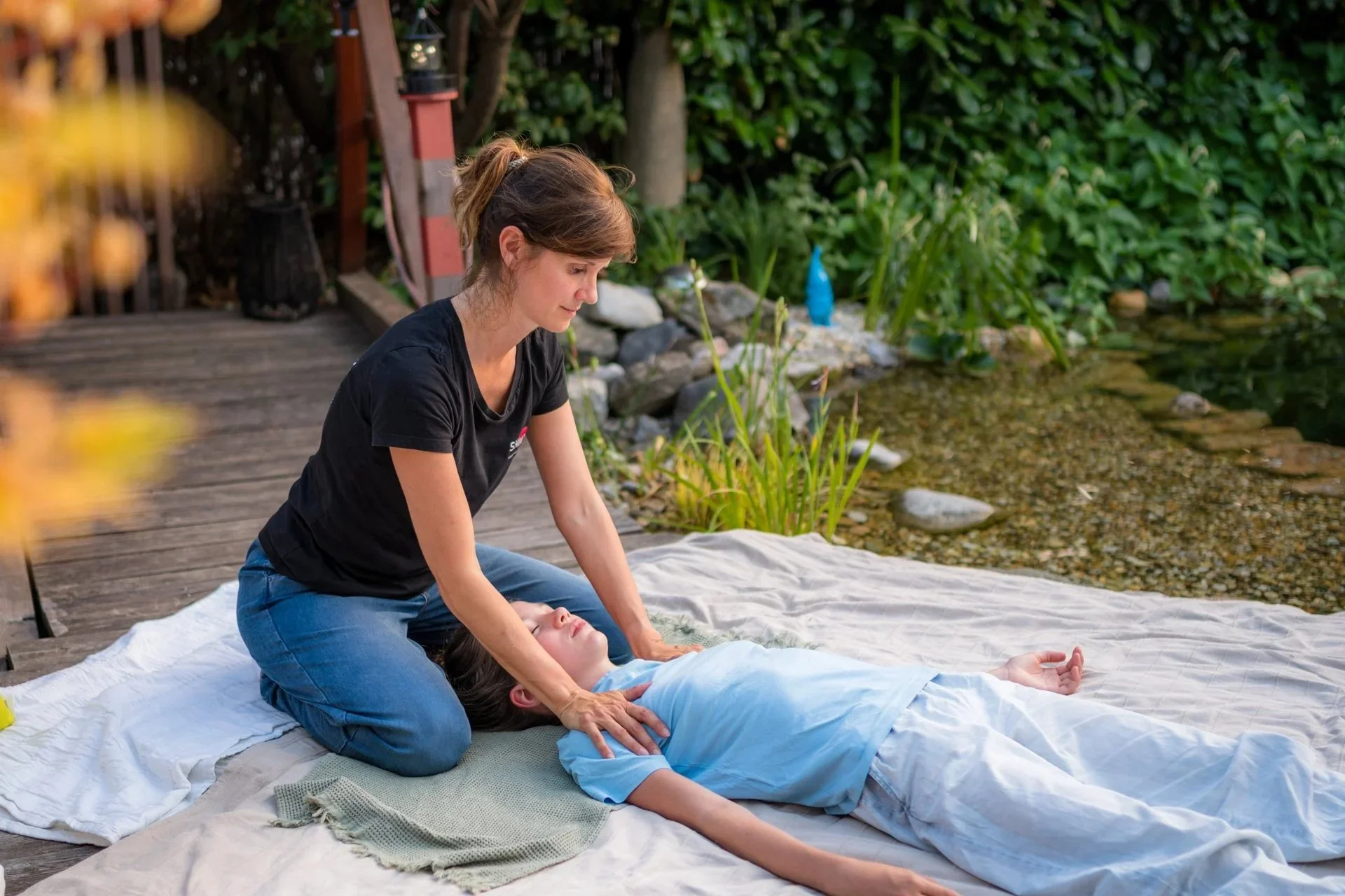 Eine Nahaufnahme von Shiatsu Lilli Lanzendorfmbei einer traumasensiblen Begleitung: Ihre Hände halten achtsam und stabilisierend die Füße eines Klienten auf der vertrauten weißen Shiatsu-Matte. Der enge Fokus unterstreicht das Angebot 'Mehr Z