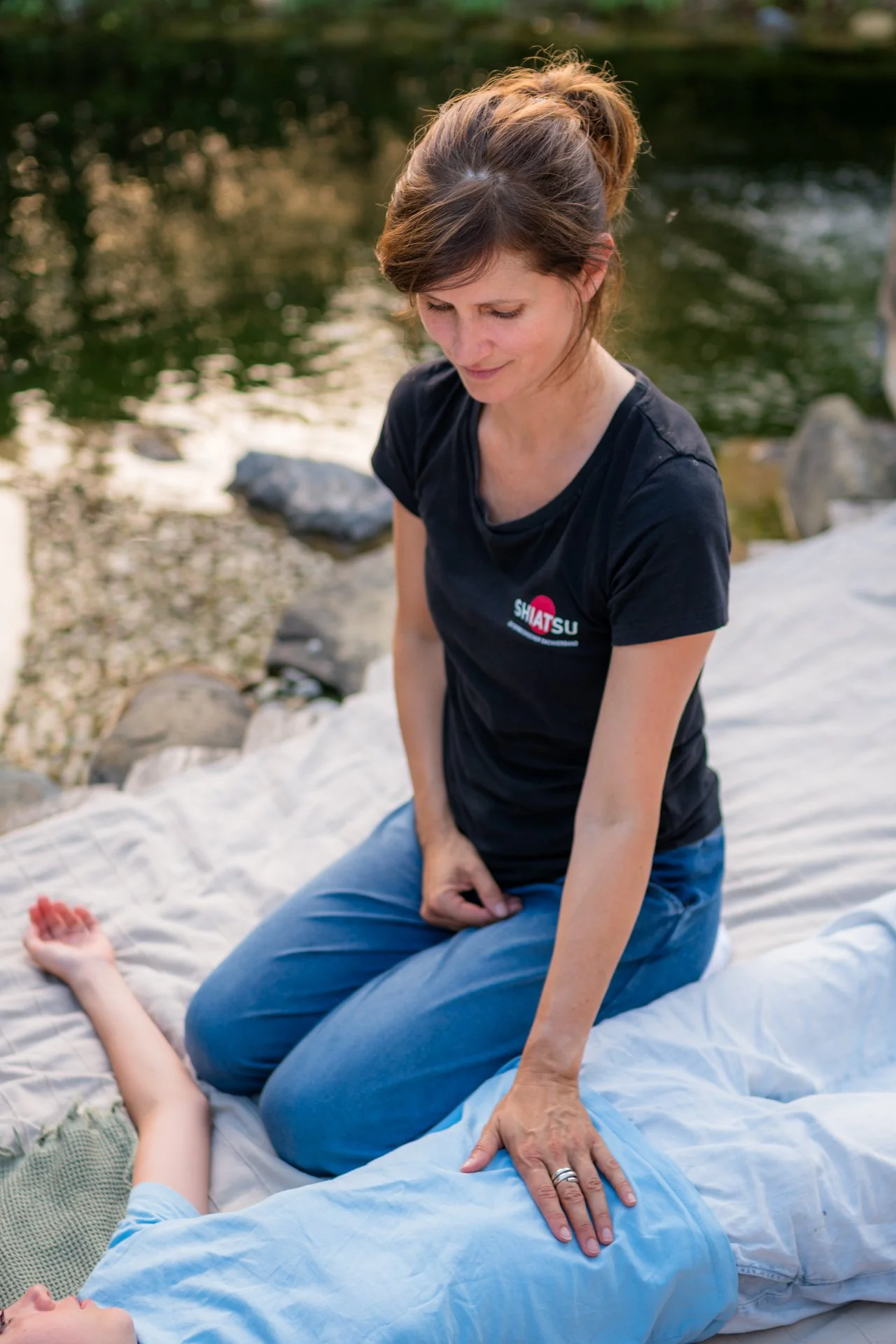 Shiatsu-Einheit am Wasser: achtsame Berührung entlang der Meridiane bei einer liegenden Klientin
