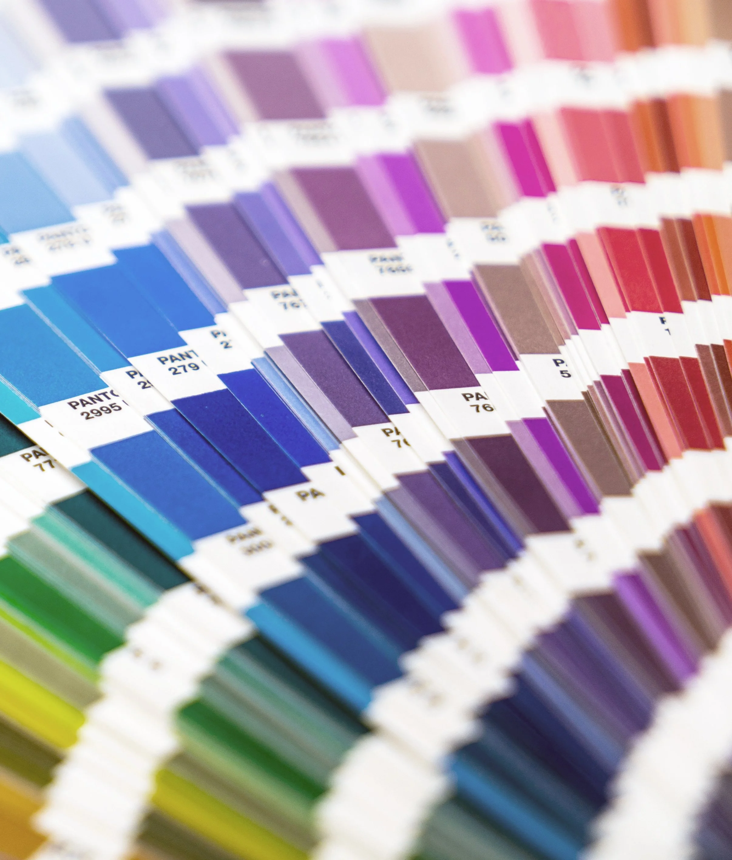 Close-up of a fan deck of color swatches arranged in a rainbow gradient from blue to purple to red and yellow.