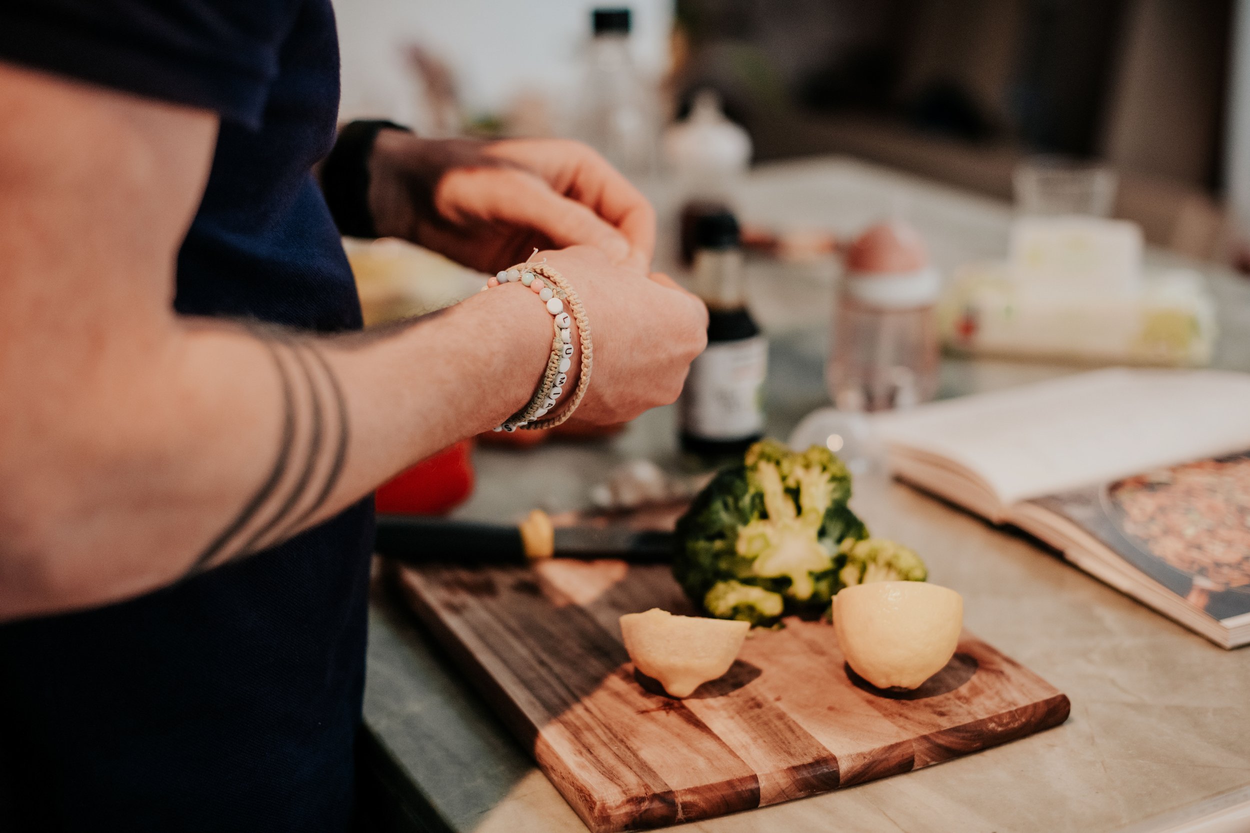 Person slicing vegetables on a wooden cutting board in a kitchen.