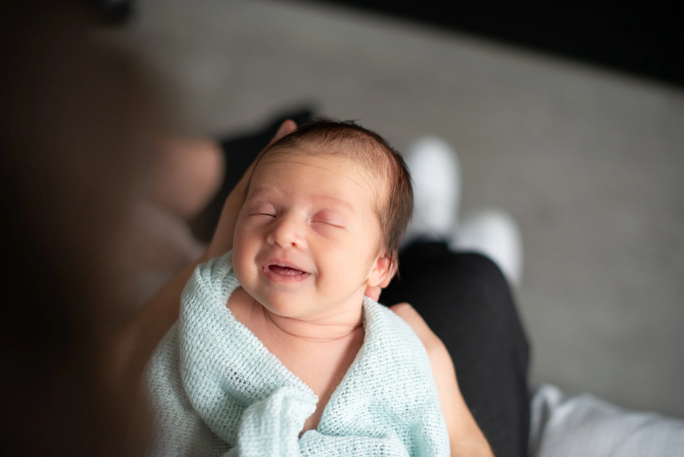 newborn met prachtig lachje in de handen van haar mama tijdens foto reportage