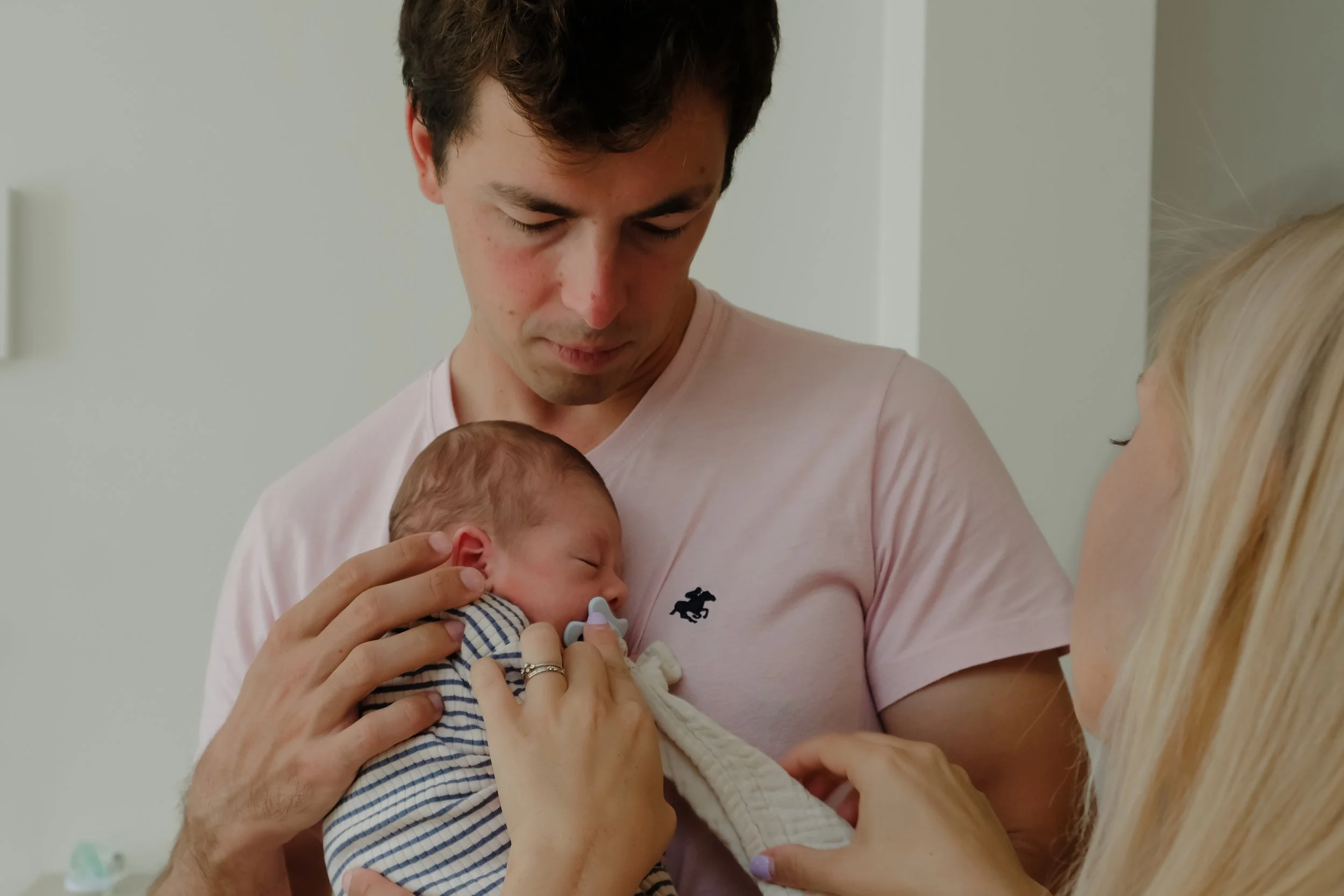 A family holding a newborn baby in a hospital room.