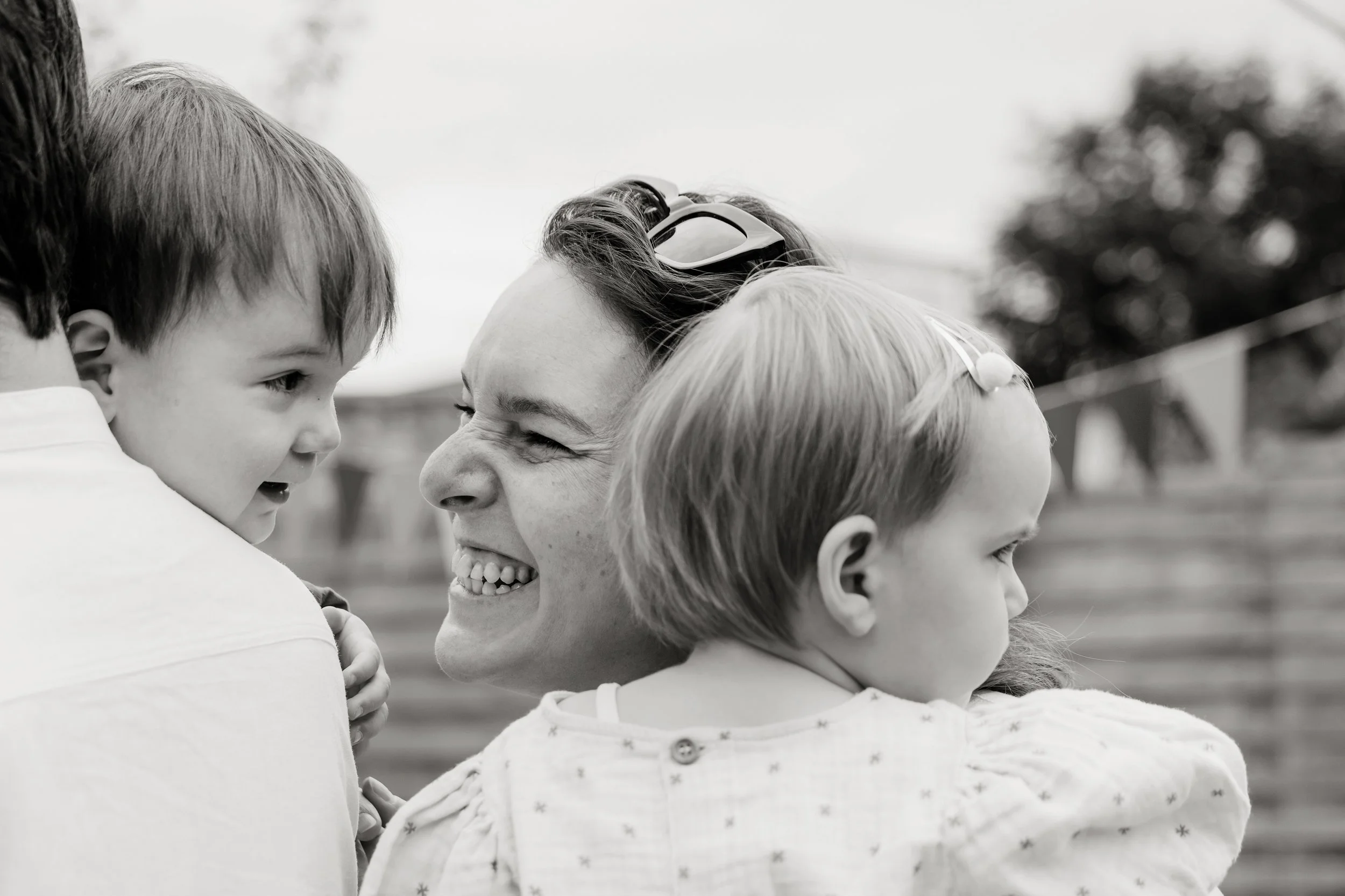 Group of children and an adult hugging and smiling outdoors.