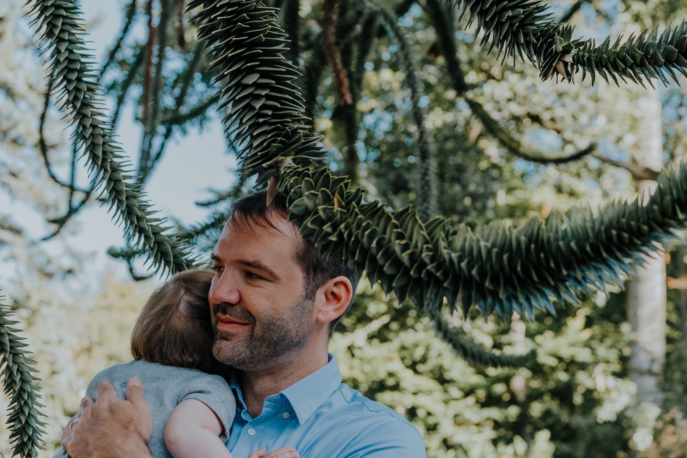 papa knuffelt zijn dochtertje liefdevol onder een prachtige boom