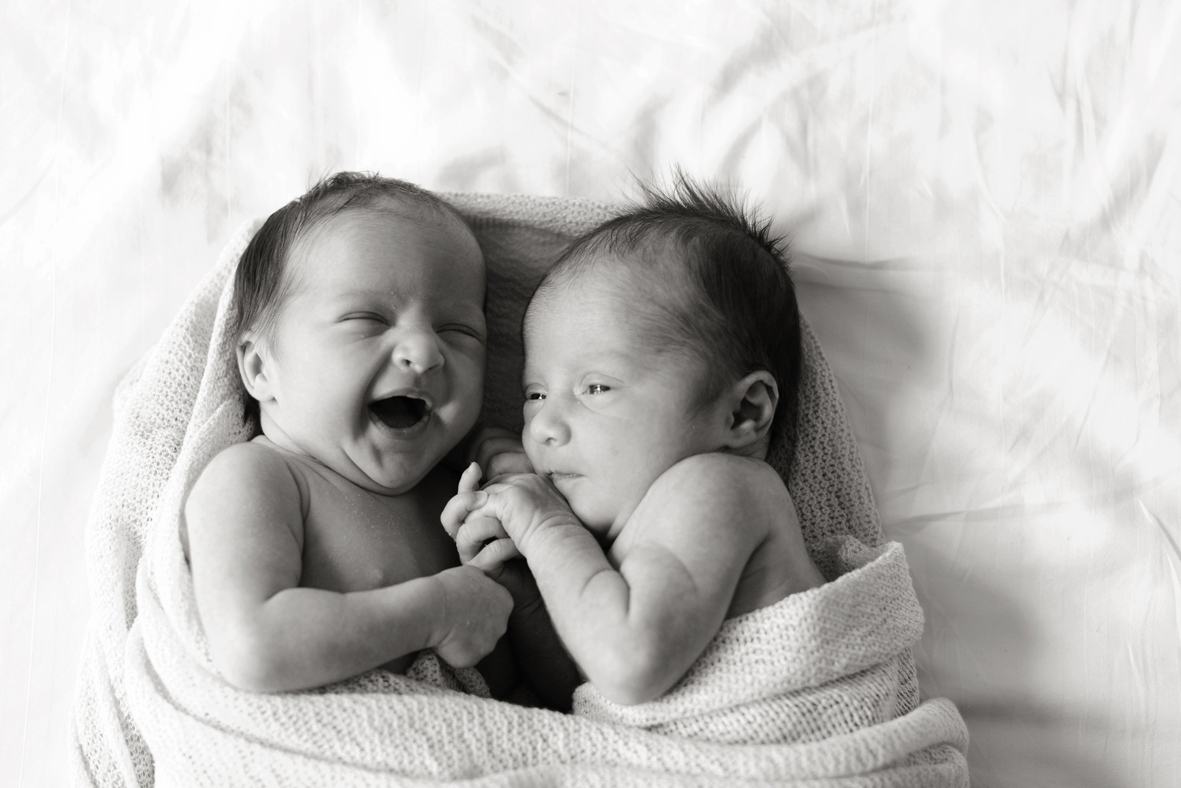 tweeling van een paar weken die voor het eerst samen in een dekentje liggen en dolgelukkig zijn tijdens documentaire newbornshoot