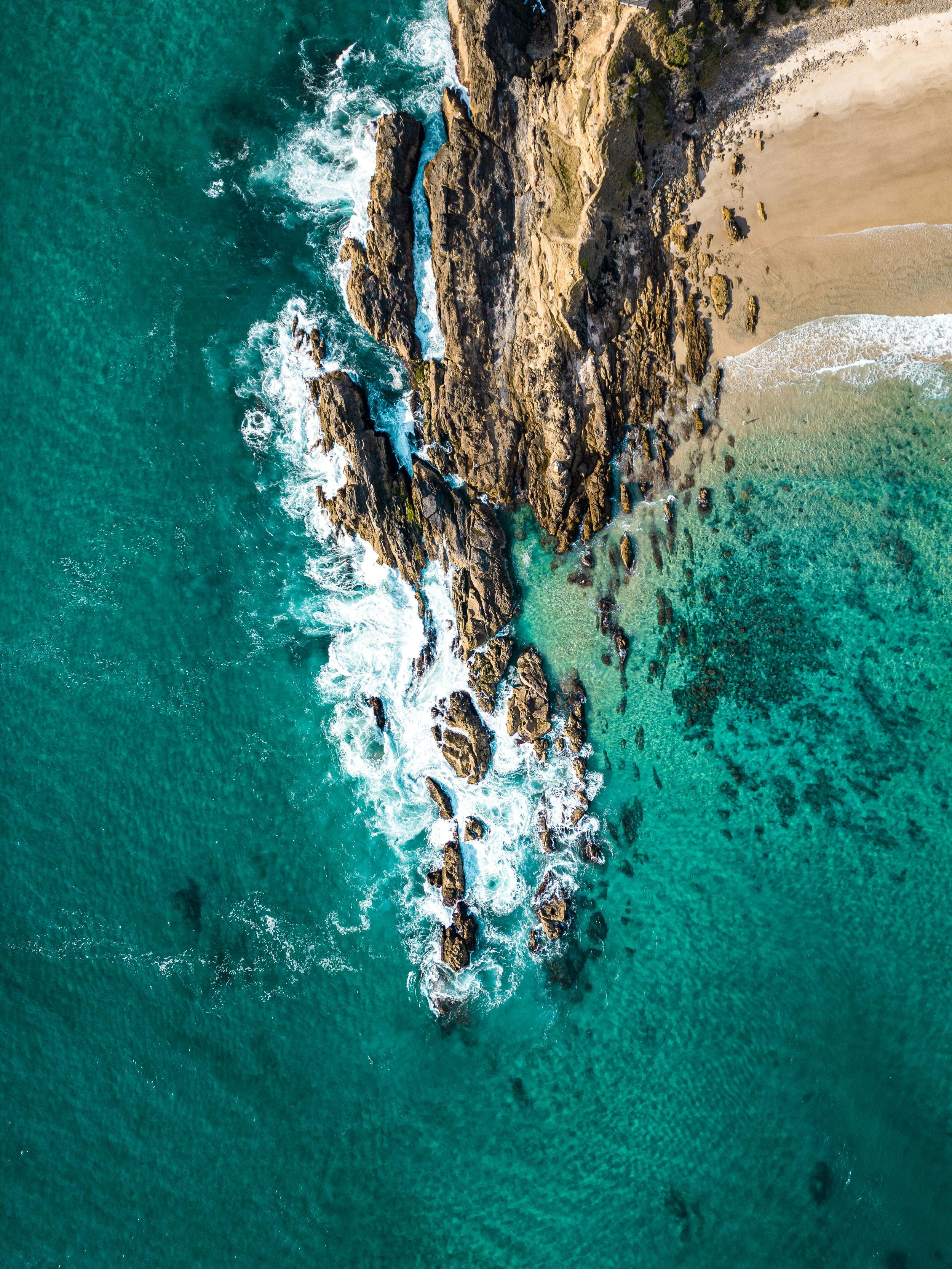 Aerial view of the Byron Bay coastline with ocean waves and natural surroundings.