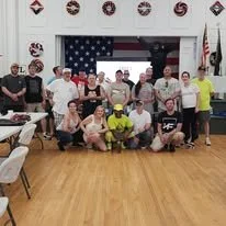 Group of people, including a firefighter, gathered in a room with American flags and patriotic decorations, posing for a photo.