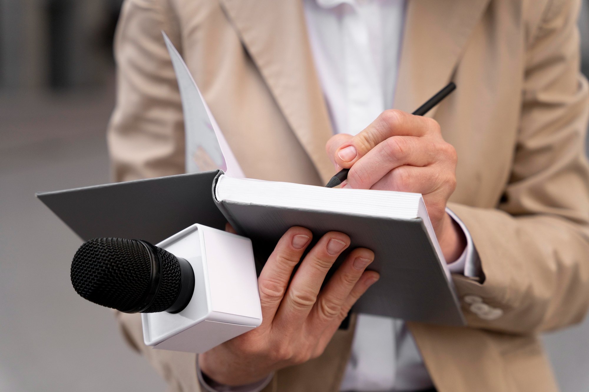 Un journaliste prenant des notes dans un carnet avec un micro à la main.
