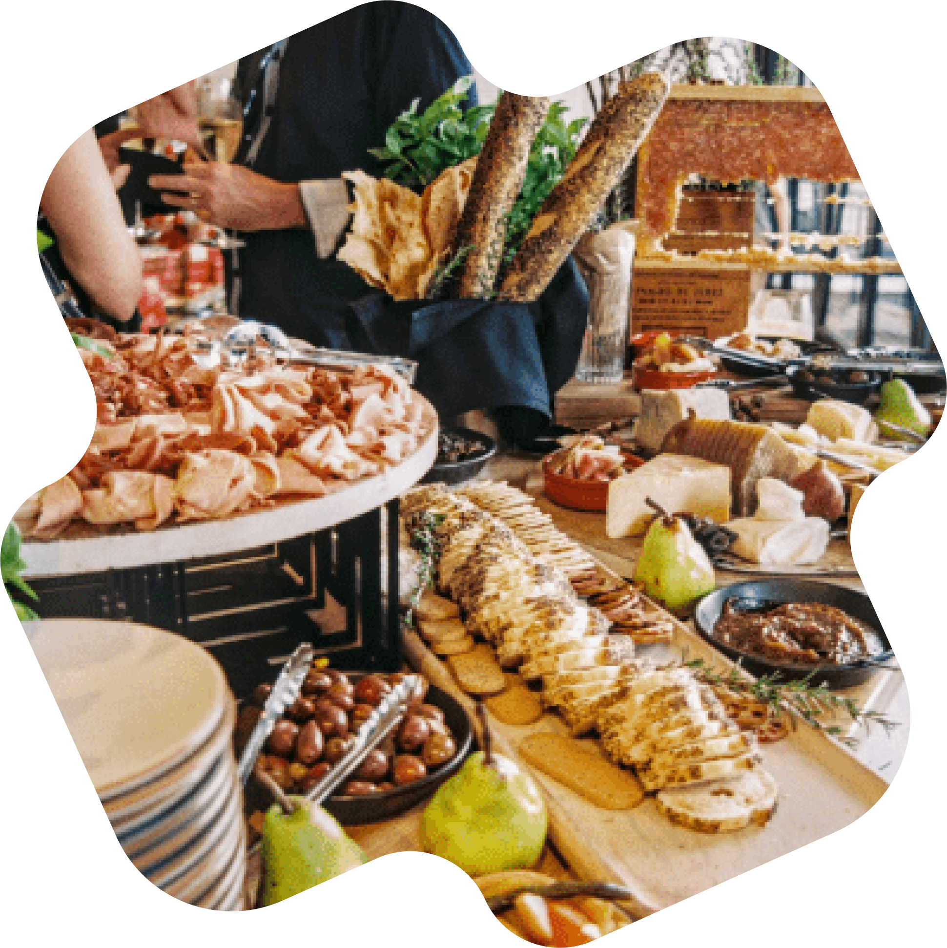 Table de buffet avec charcuterie, fromage, pain, olives, et fruits.