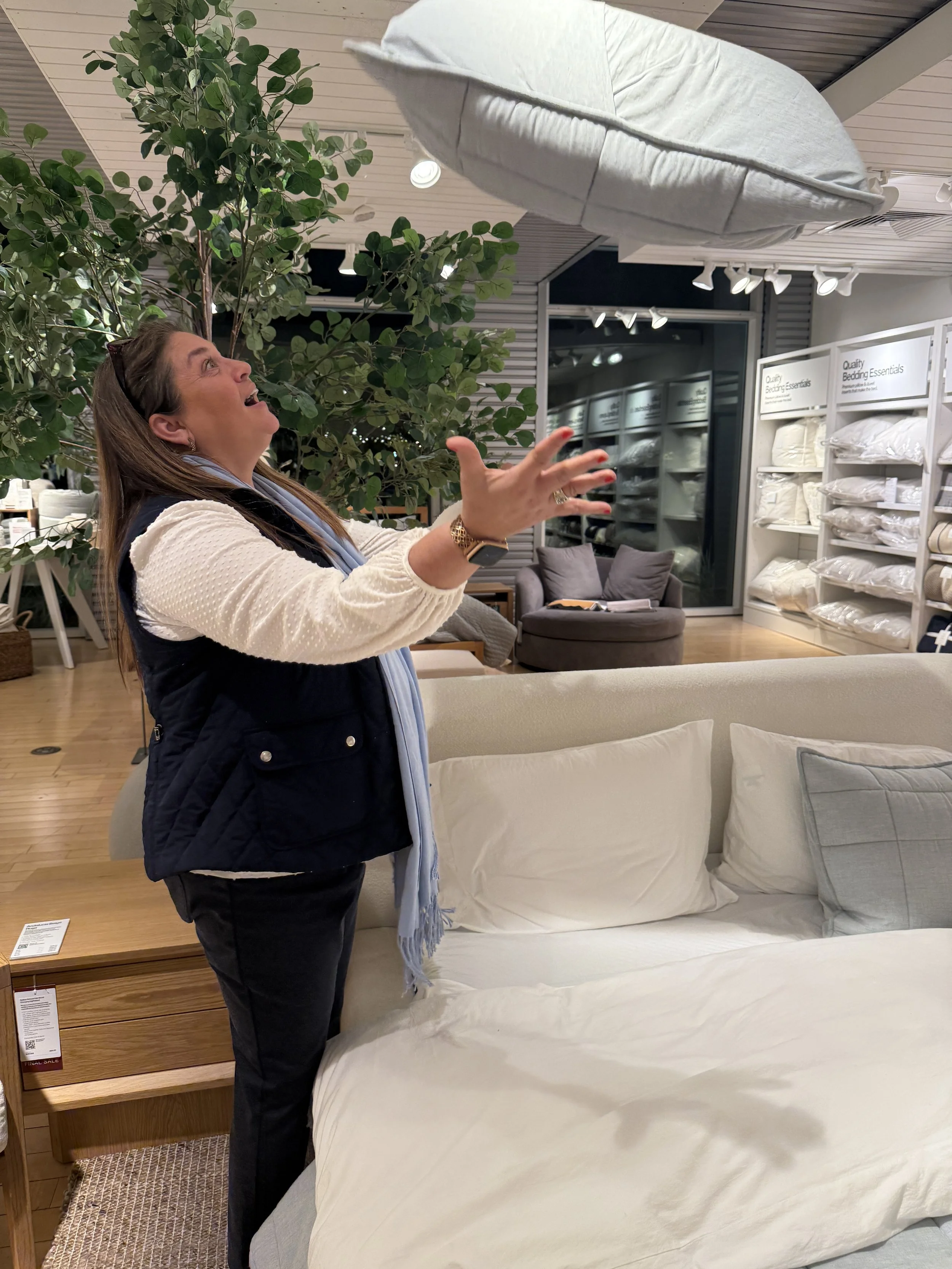 A woman in a store demonstrates a cloud-shaped cushion hanging from the ceiling.