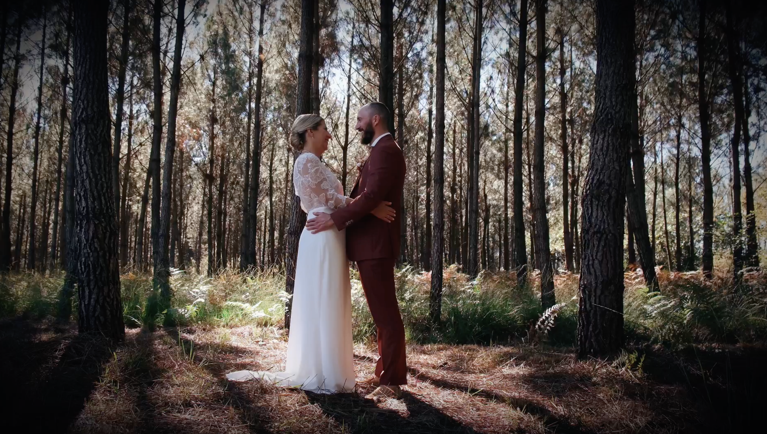 Un couple habillé en vêtements de mariage, se tenant la main dans une forêt durant l'automne.