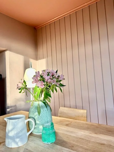 Bukett med rosa blomster i en blå vase på et spisebord