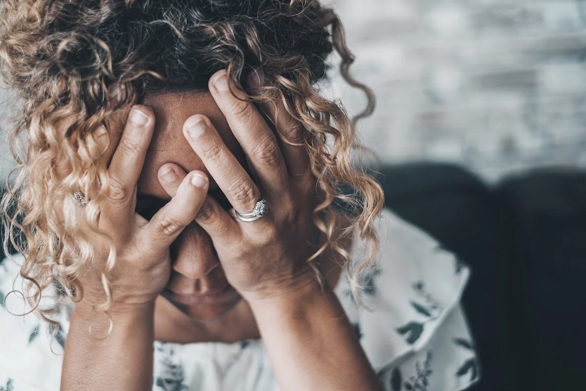 stressed woman holding her head in her hands
