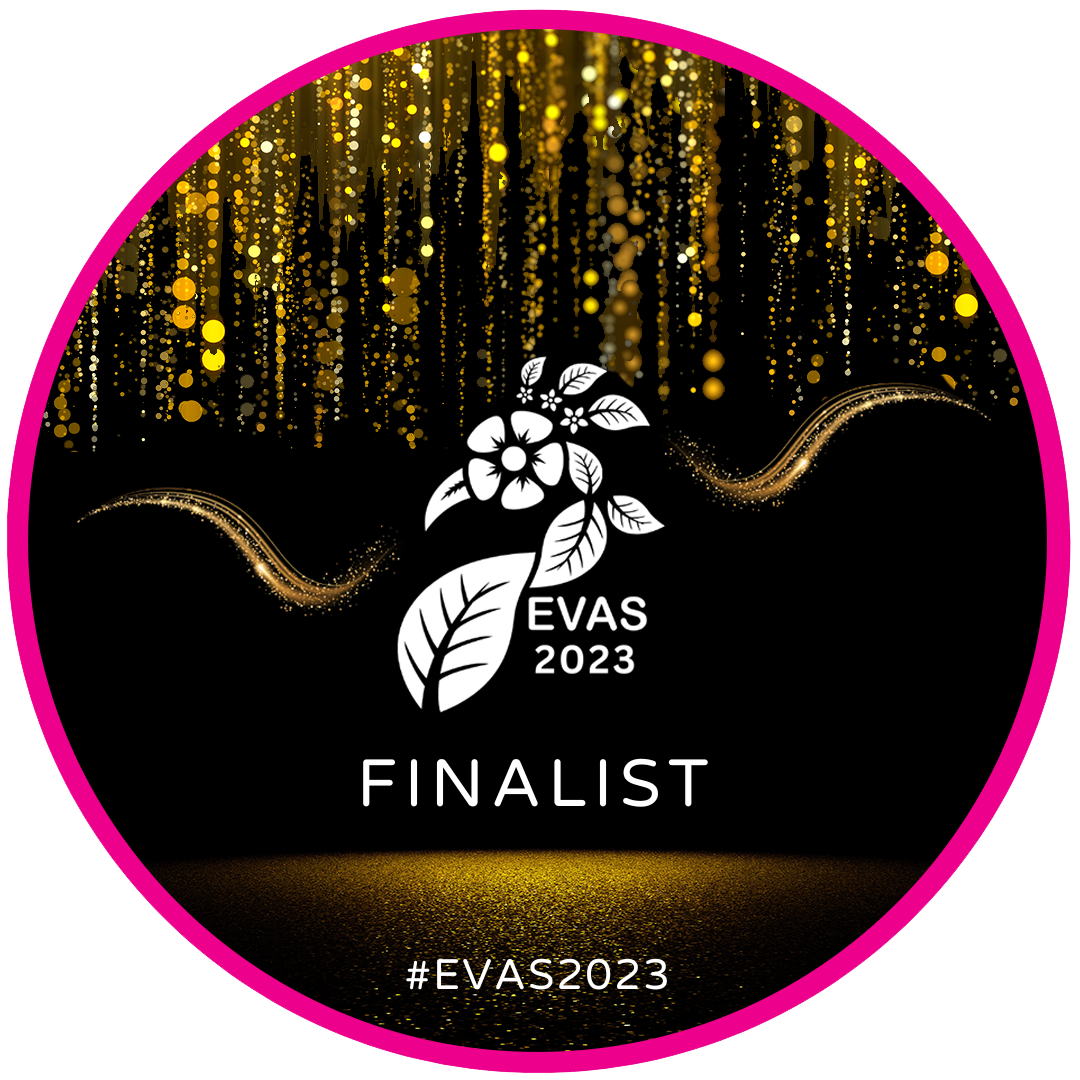 A circular badge for EVAS 2023 awards with a black background, featuring a white illustration of a flower with leaves, gold glittering vertical lines at the top, and gold sparkling wave designs. Text indicates 'FINALIST' and the hashtag #EVAS2023.