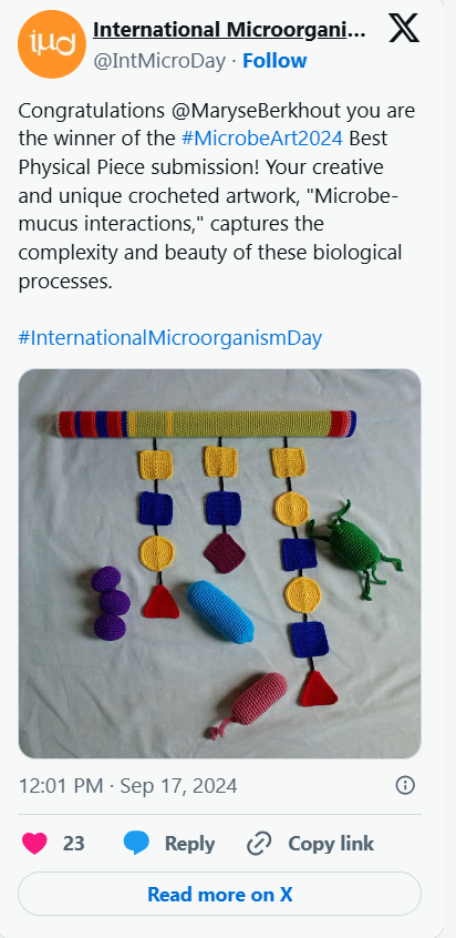 Colorful crochet artwork resembling a beaded necklace with various geometric shapes, a green crochet insect, and two crochet mice, one pink and one purple, displayed on a white surface.