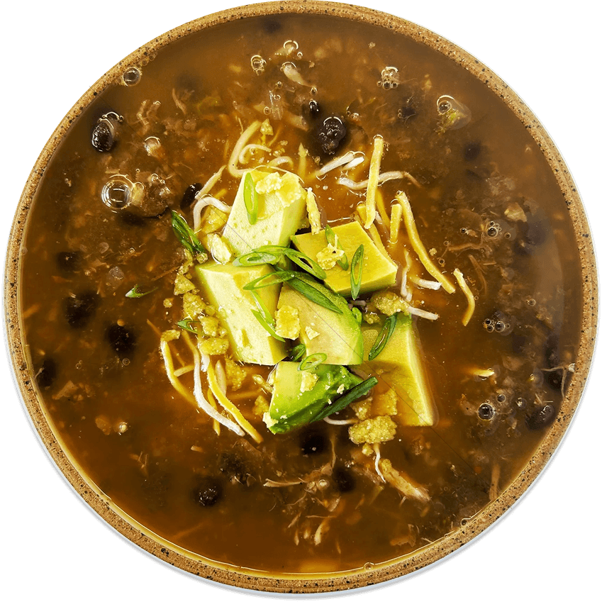 A bowl of hot soup with chunks of avocado, bean sprouts, shredded chicken, and green onions in a clear broth.
