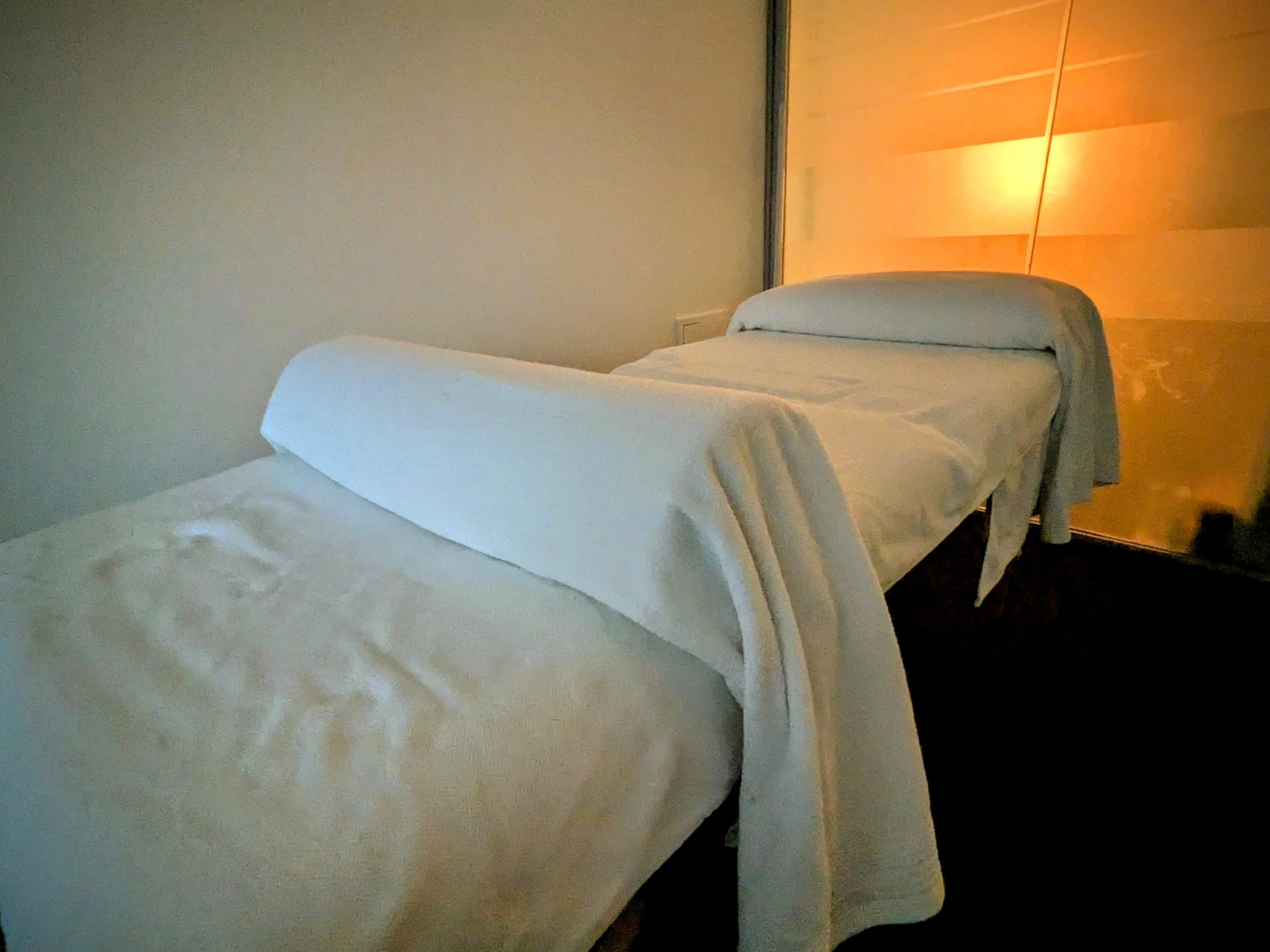 An acupuncture treatment table, with warm-toned lighting, promoting a restful, cozy, healing atmosphere