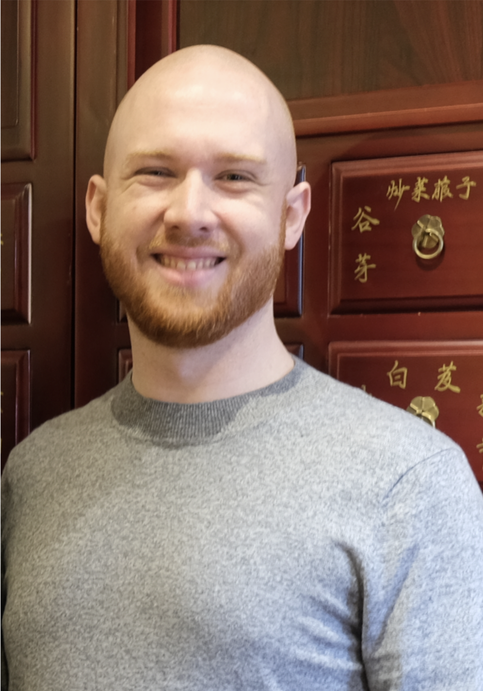 portrait photo of Felix who is wearing a grey coloured shirt, with a friendly smile on his face
