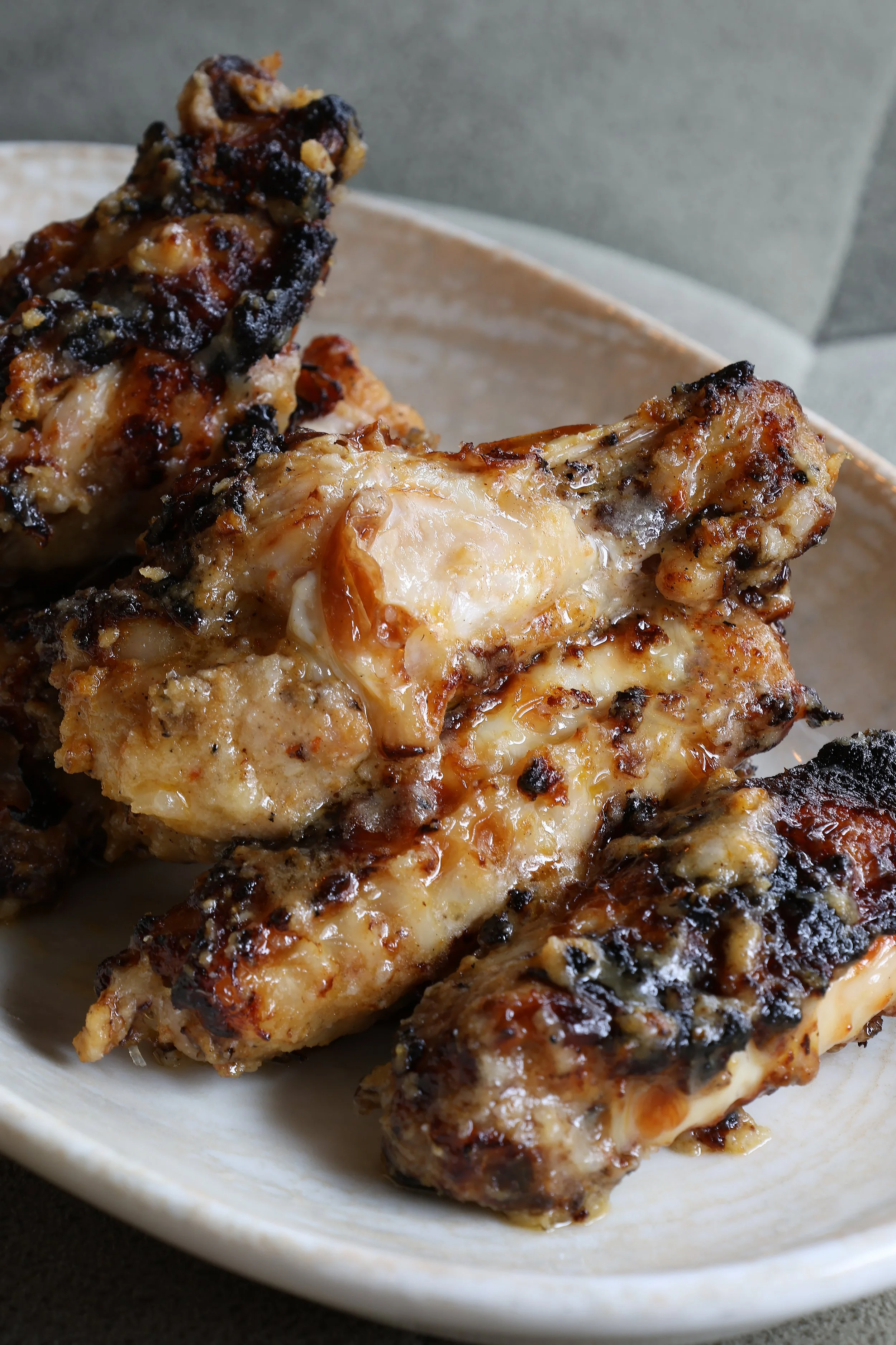 Close-up of cooked chicken drumsticks with a crispy, browned exterior, served on a white dish.