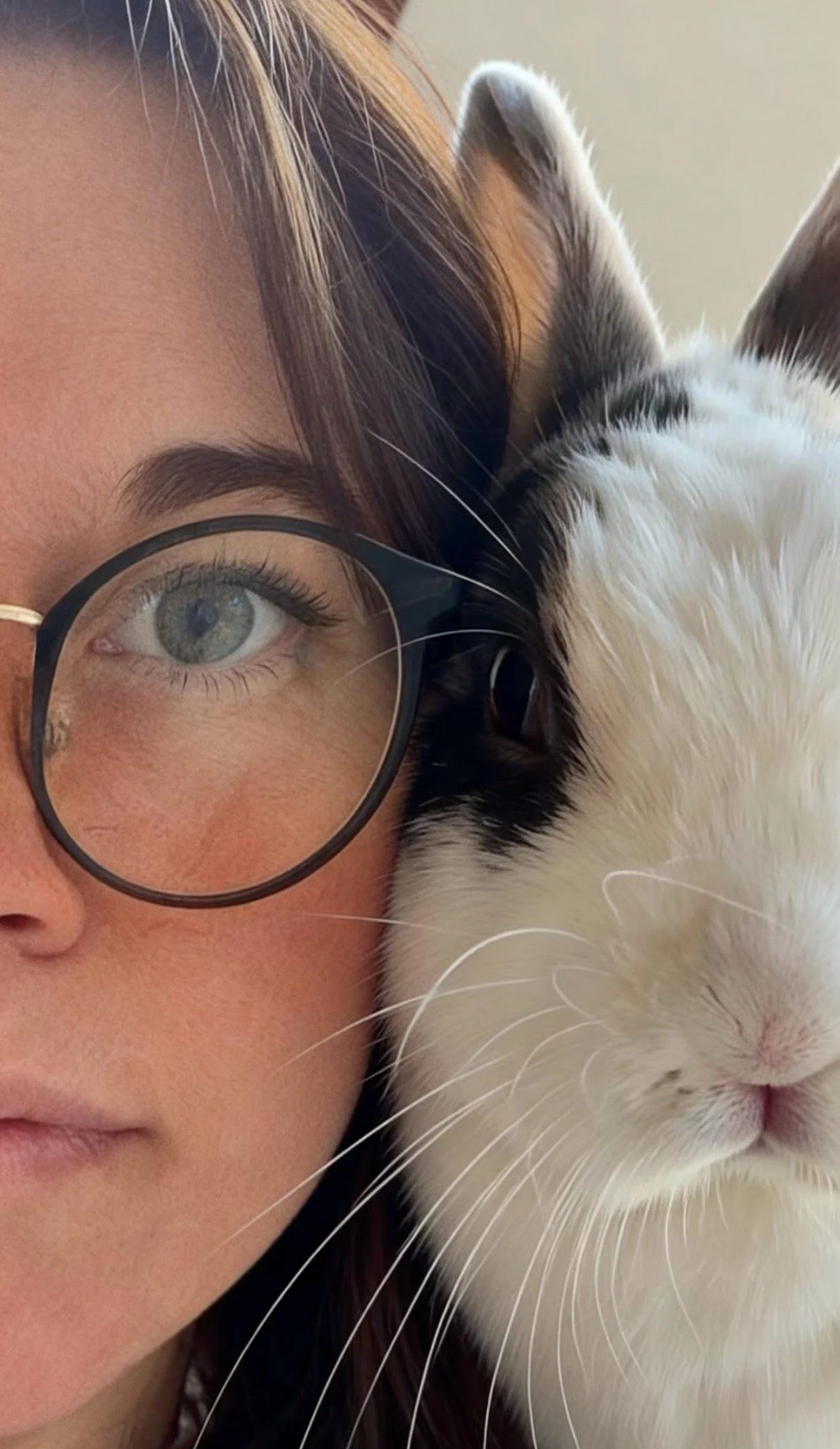 Une femme avec des lunettes et un lapin blanc et noir, tous deux regardant l'objectif.