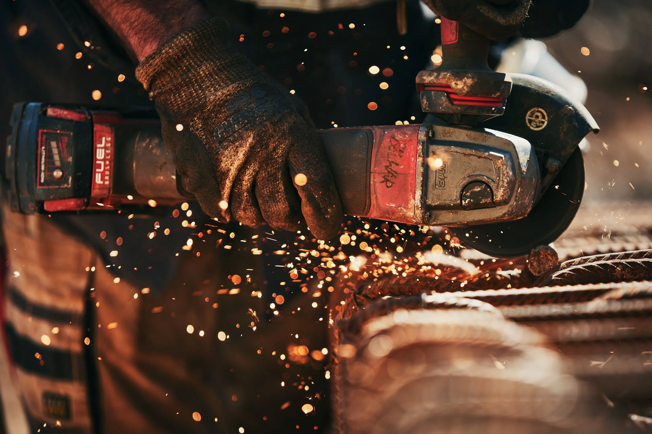 Person using a reciprocating saw to cut a piece of metal, sparks flying from the cutting process.