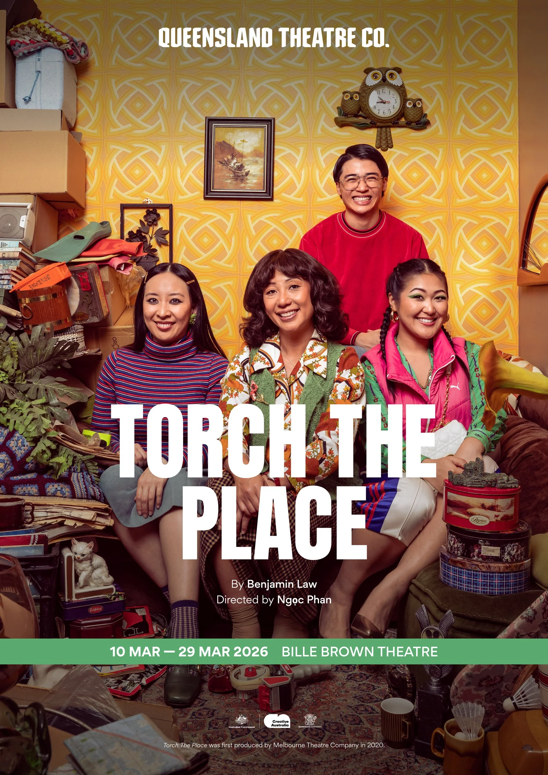 The poster for the play 'Torch the Place' at Bille Brown Theatre features five actors in a cluttered room with various objects, plants, and a cat. The background has yellow patterned wallpaper, a framed painting, and a clock with owl decorations. The