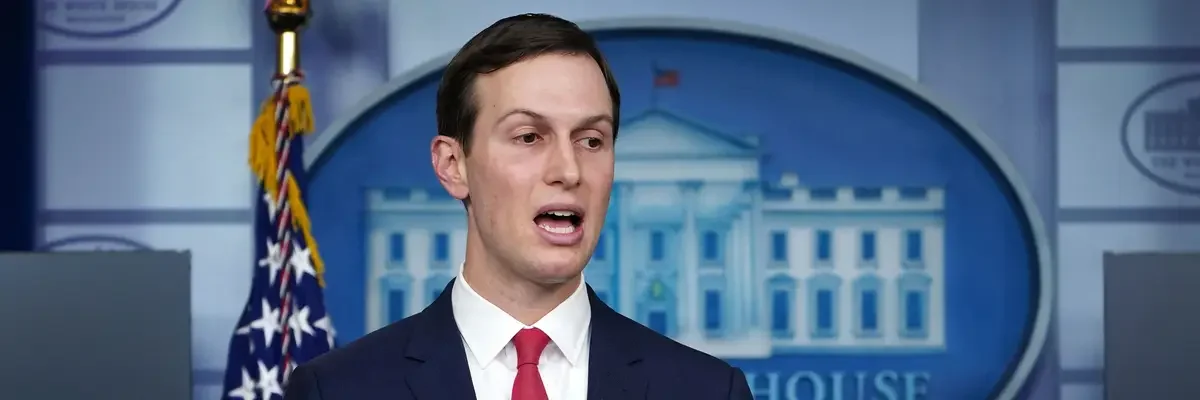 A man in a suit speaking at a press briefing with the White House emblem in the background.