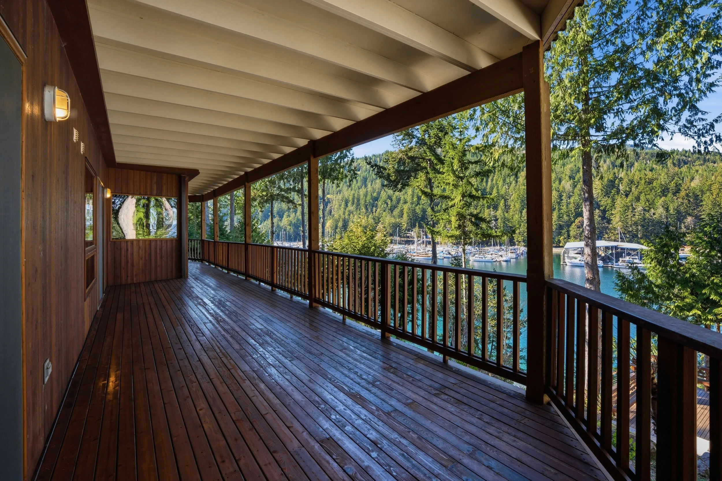 Wooden balcony overlooking a marina with boats and surrounded by trees.