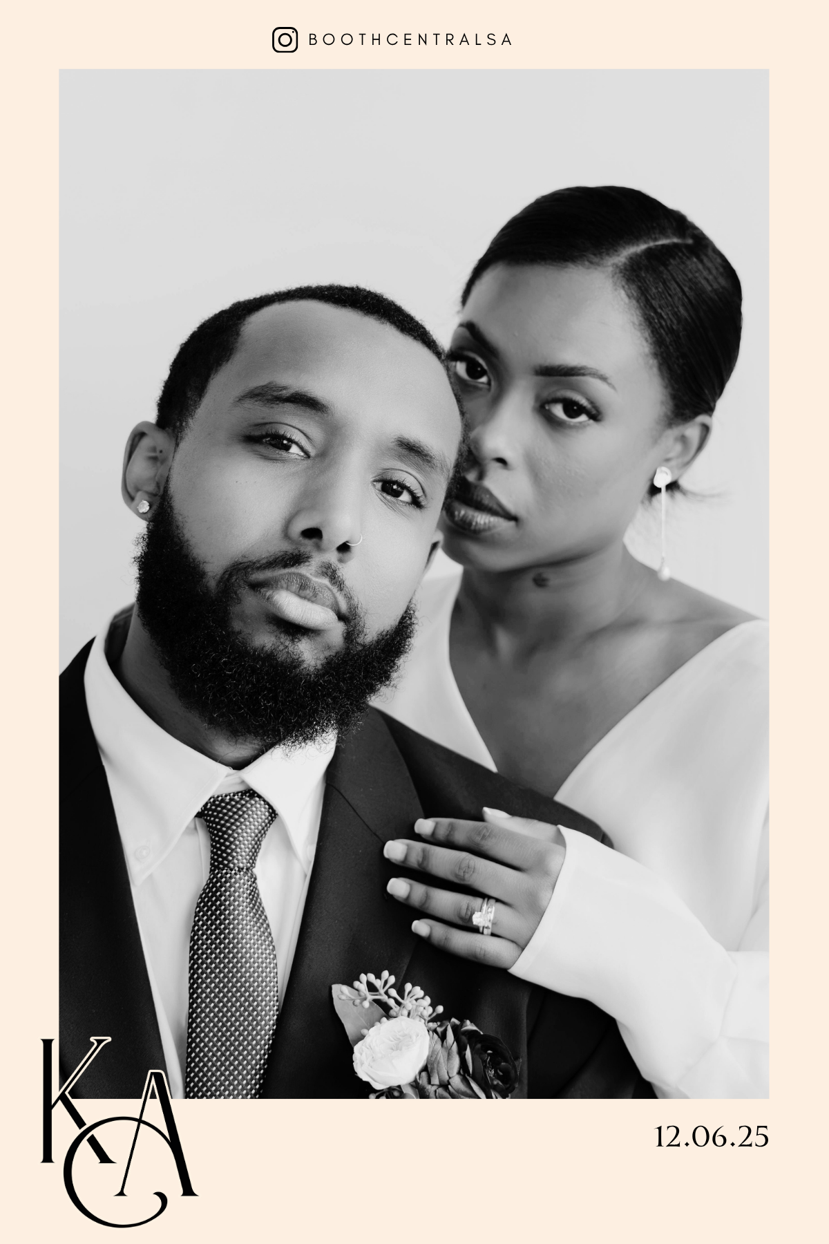 Black and white photo of a couple in wedding attire. The man has a beard, is wearing a suit and tie, with a flower boutonniere. The woman has short, styled hair, is wearing a dress, and has a ring on her finger. The bottom-left corner features initials and a date, 12.06.25.
