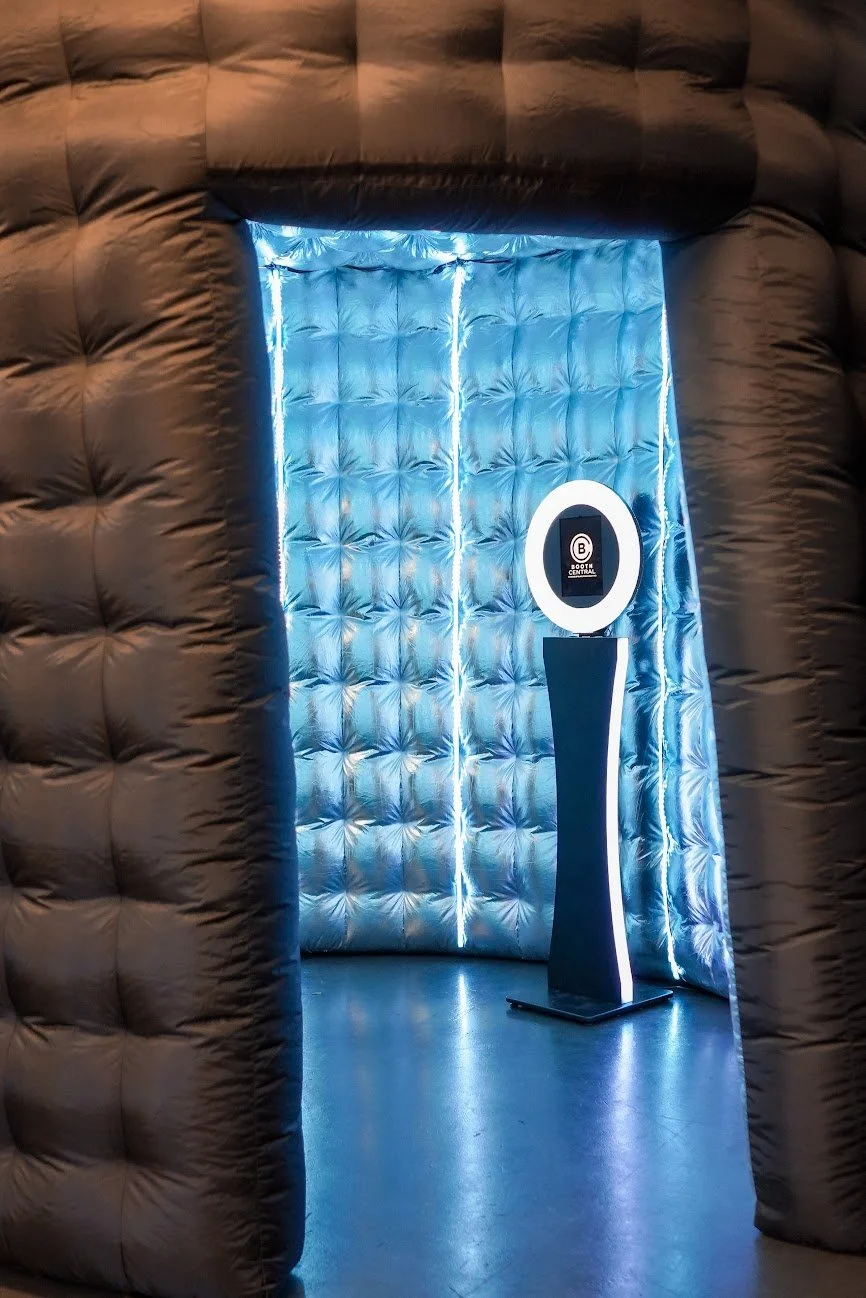 Photo of a digital check-in kiosk in a dimly lit, padded, inflatable structure with blue lighting.