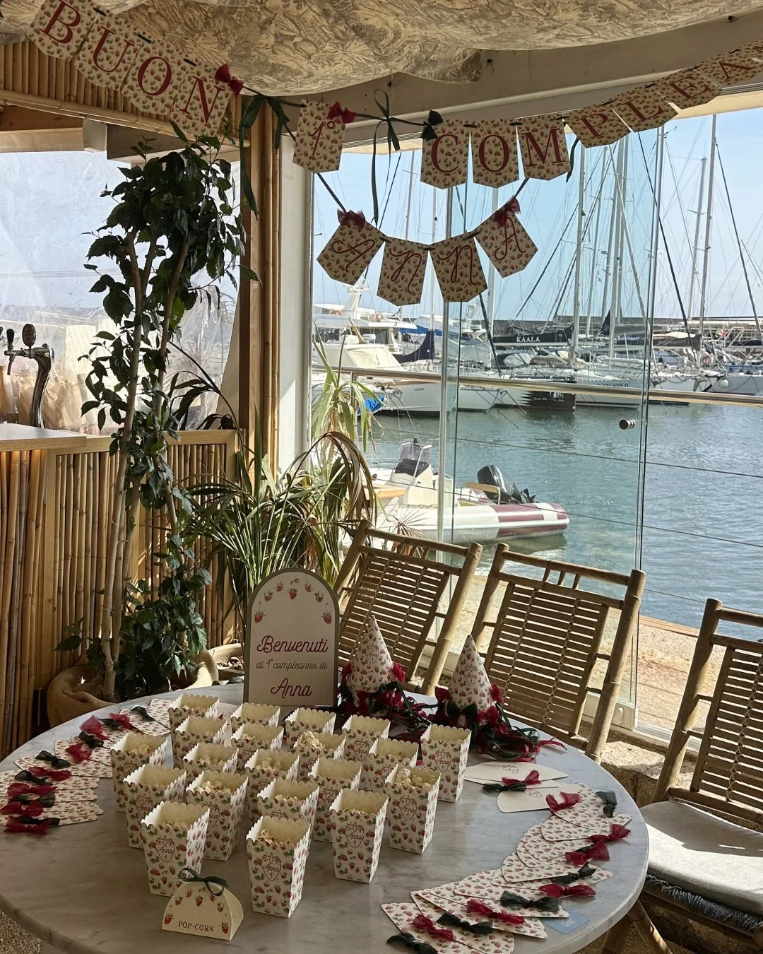 Allestimento completo per compleanno a tema fragole, con festone, ventagli e dettagli coordinati, ambientato in una location sul mare in Sardegna.