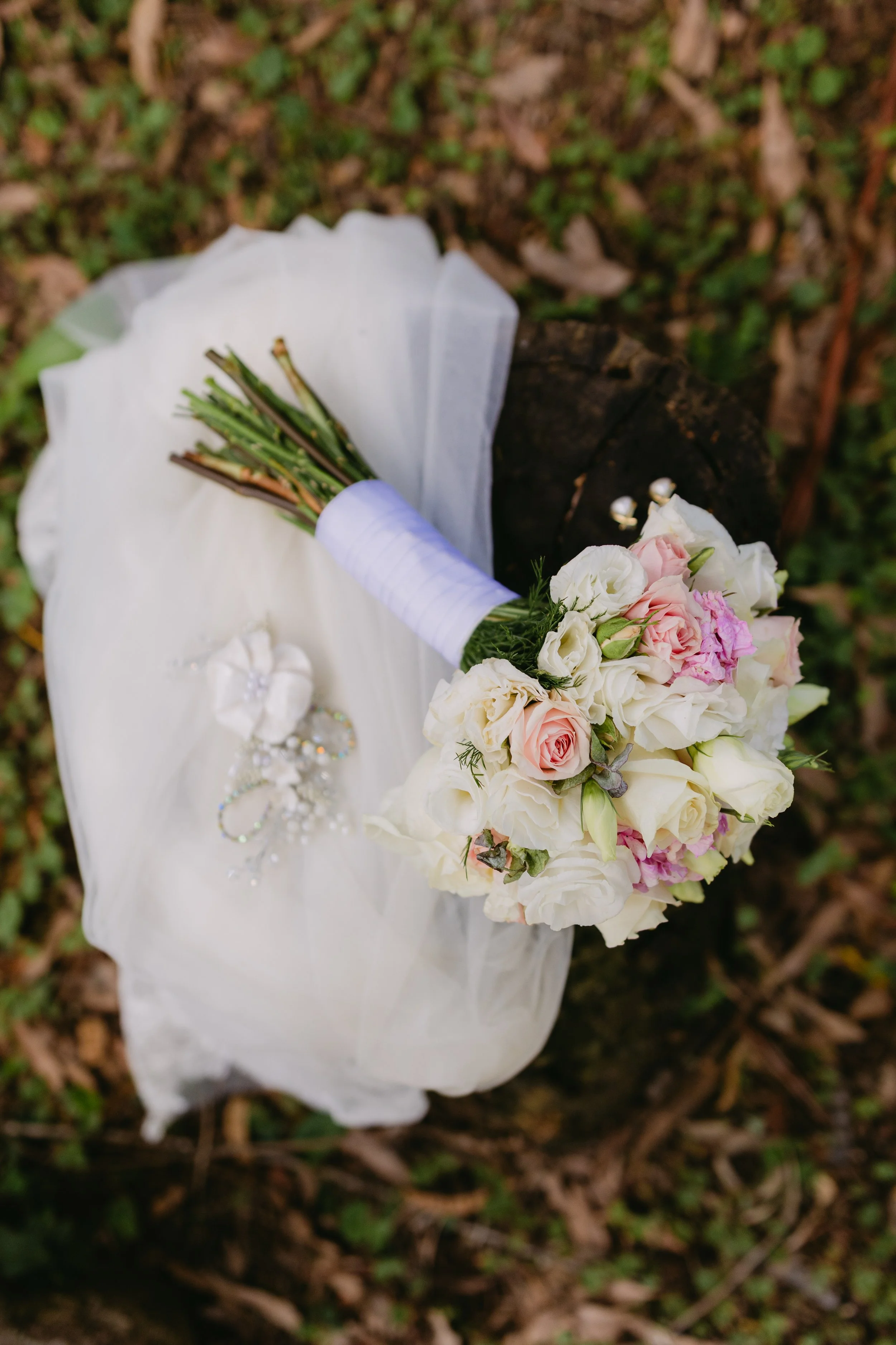Ramo de flores blancas y rosadas sobre un tronco en el bosque.