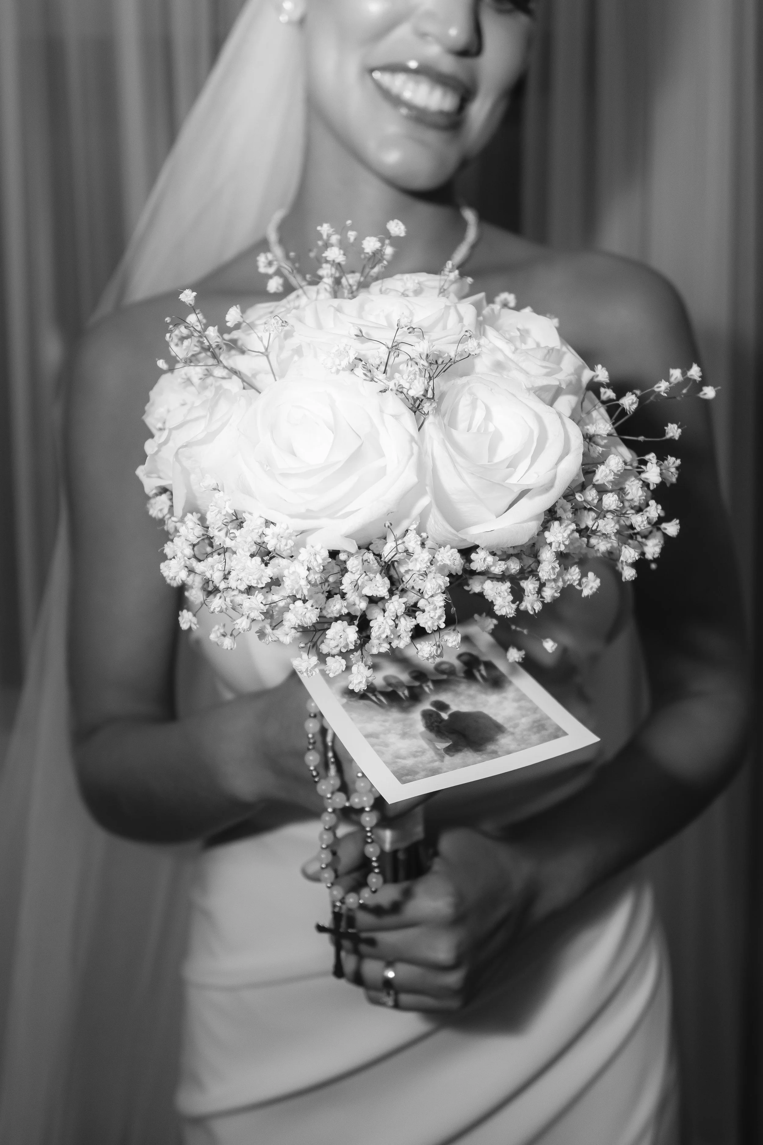 Mujer con vestido de novia sosteniendo un ramo de flores, con una fotografía en las manos, en una ambiente interior.