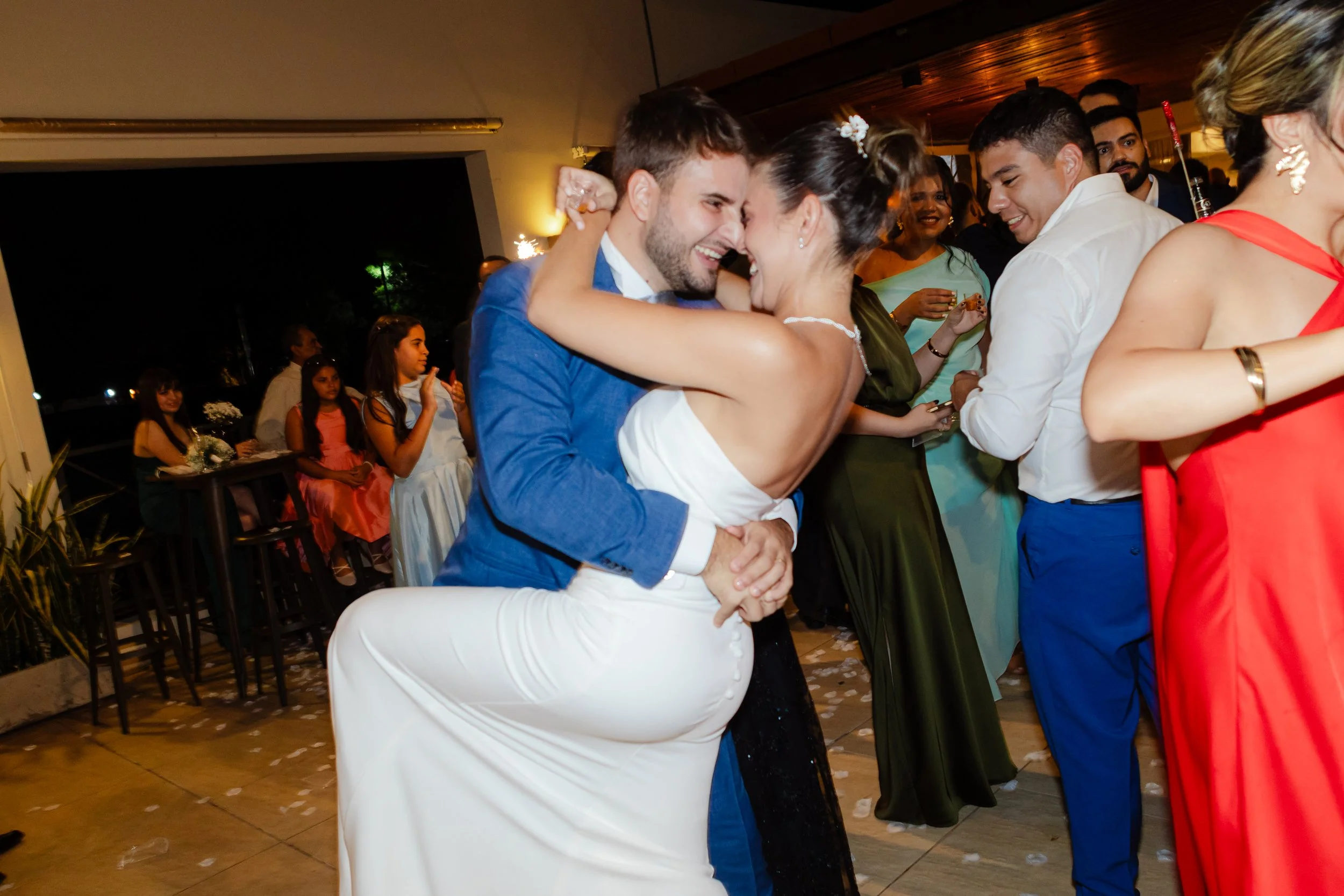 Pareja de recién casados bailando y abrazándose en su boda, rodeados de invitados felices.