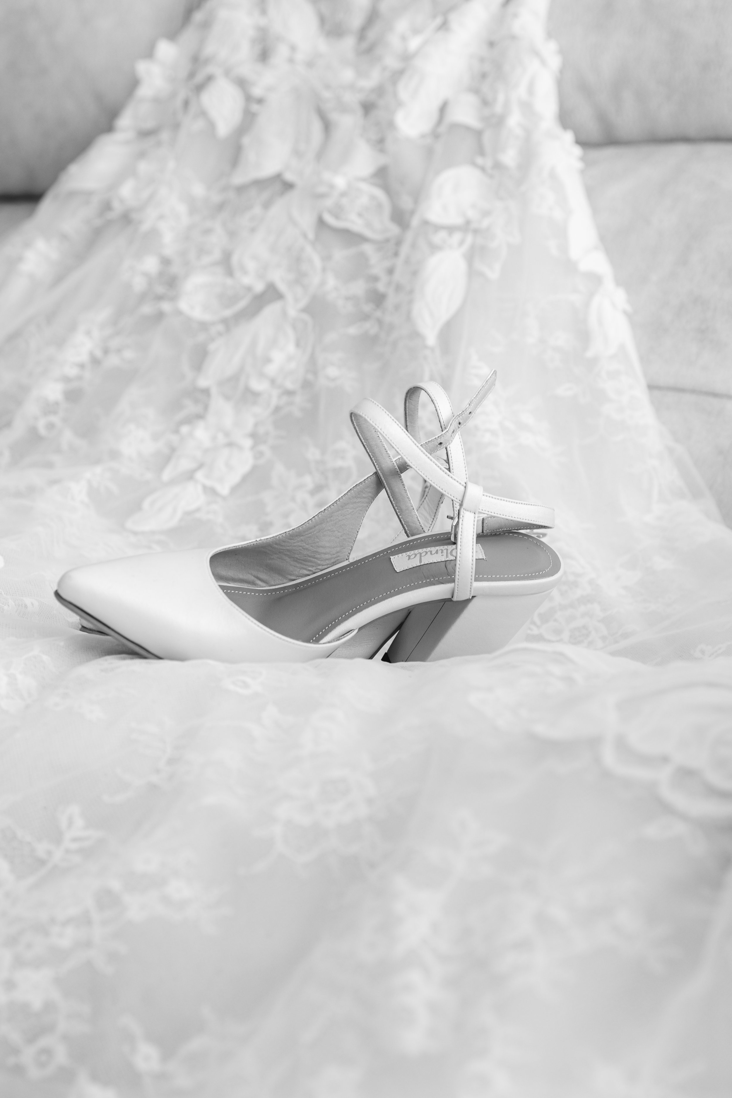 Zapatos blancos de tacón en una tela de encaje con detalles florales.