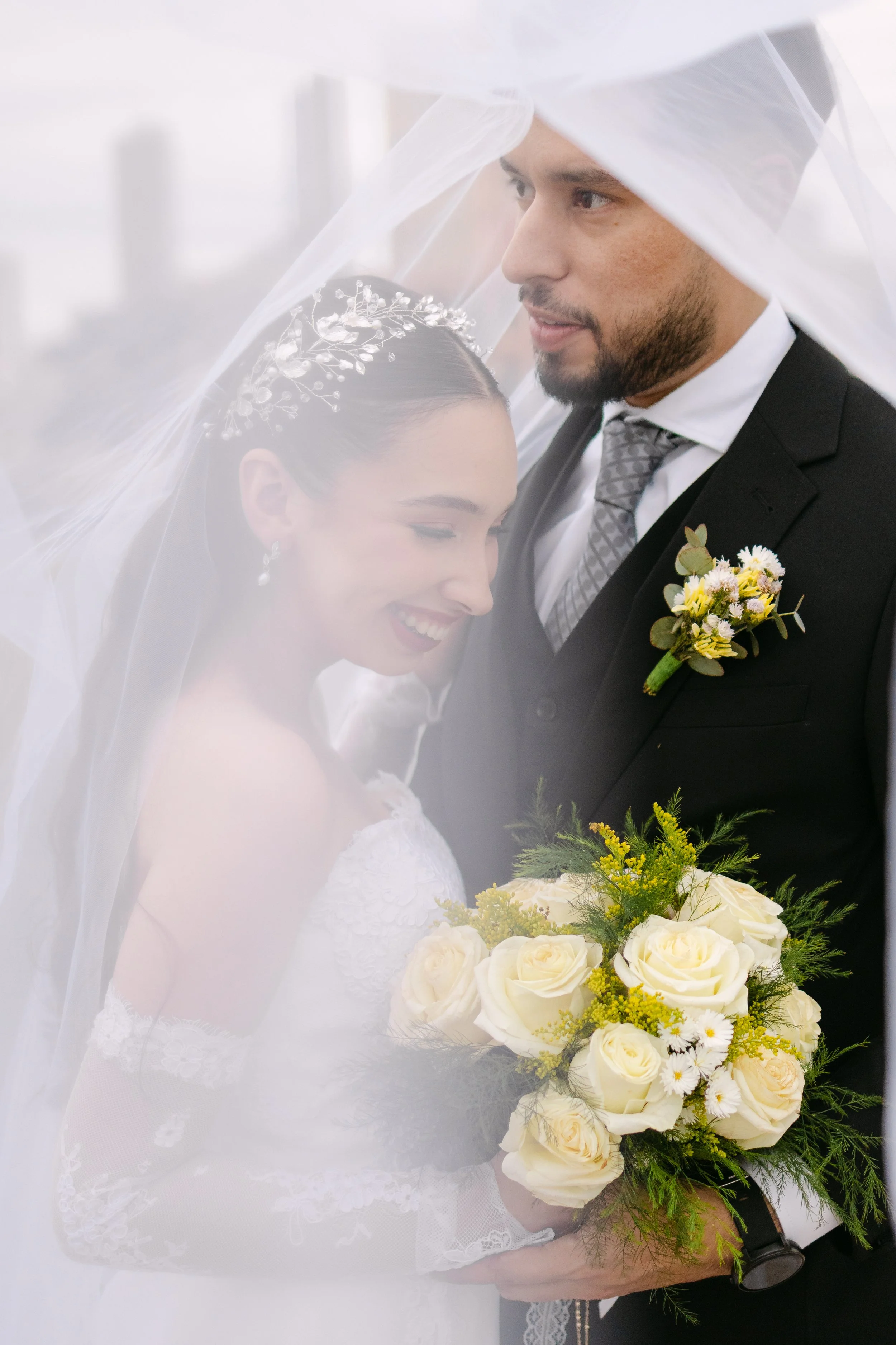 Una pareja de novios en una boda, con la novia sosteniendo un ramo de rosas blancas y la pareja usando atuendos formales, con detalles de vestimenta y accesorios típicos de una boda.