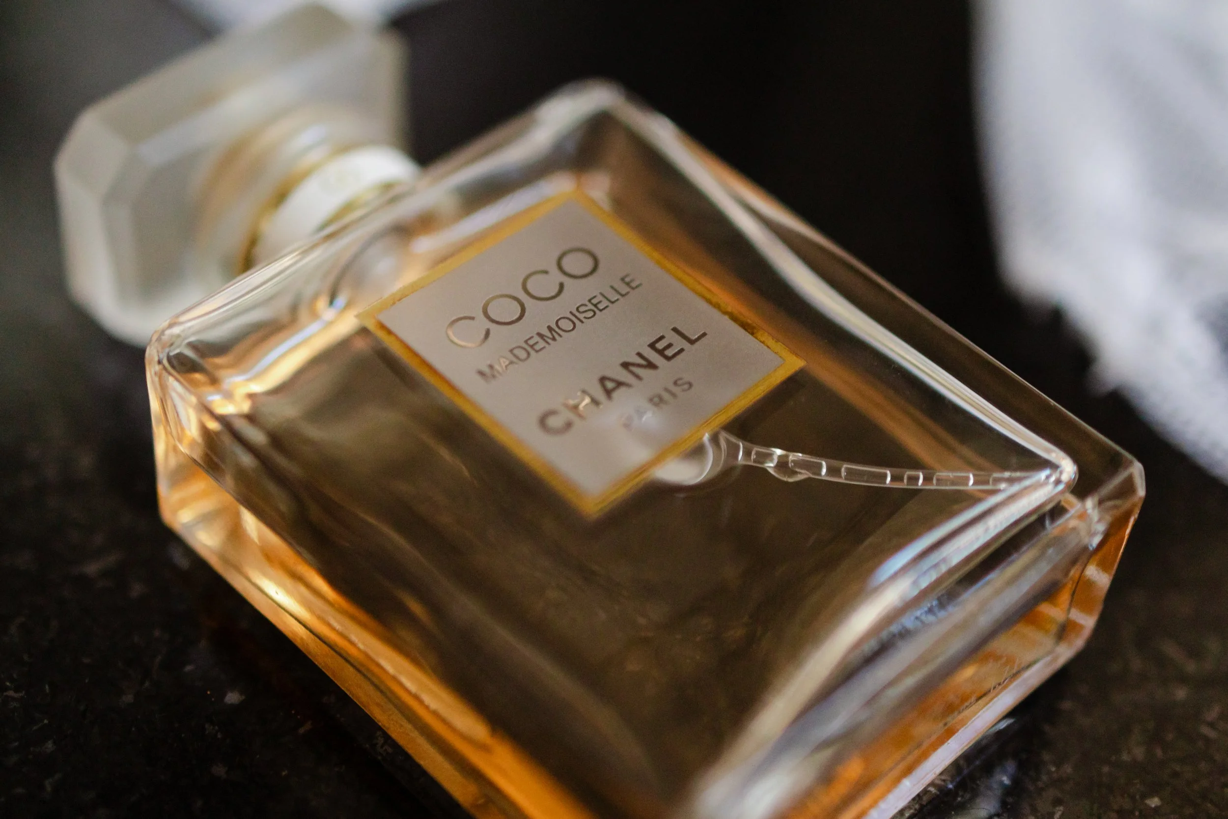 Frasco de perfume Chanel Coco Mademoiselle en ángulo, colocado sobre una superficie oscura.