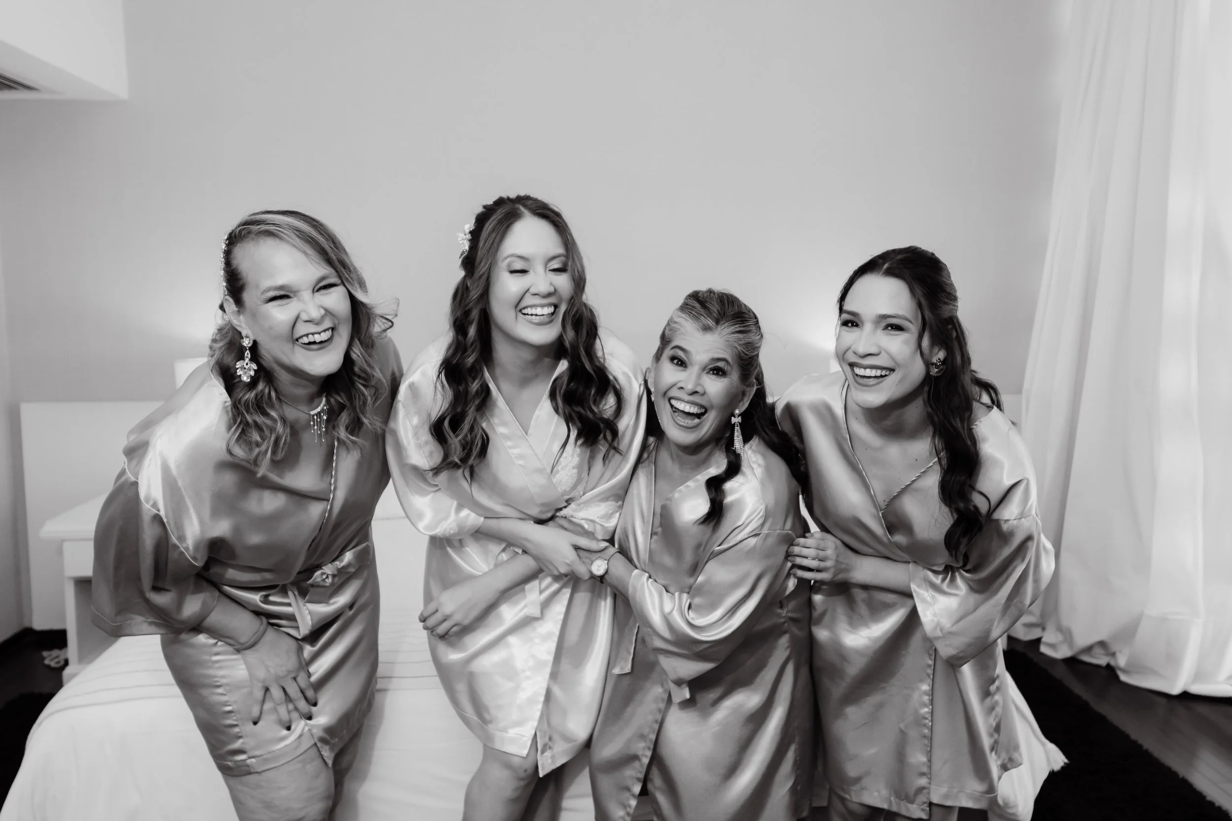 Cinco mujeres en bata de seda sonriendo y posando juntas en una habitación.