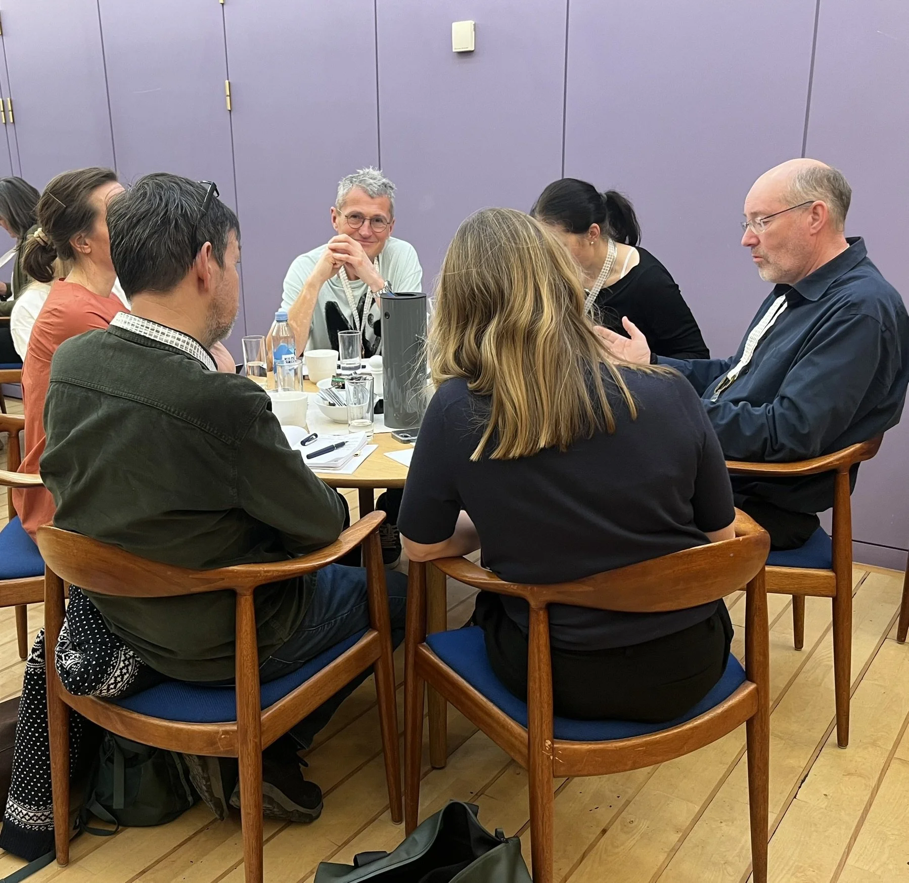 Rundbordssamtaler ved Symposium i Forum for En Ny Grøn Oplysningstid. En gruppe mennesker sidder omkring et rundt bord i et mødelokale, idet de ser ud til at være i en diskussion.