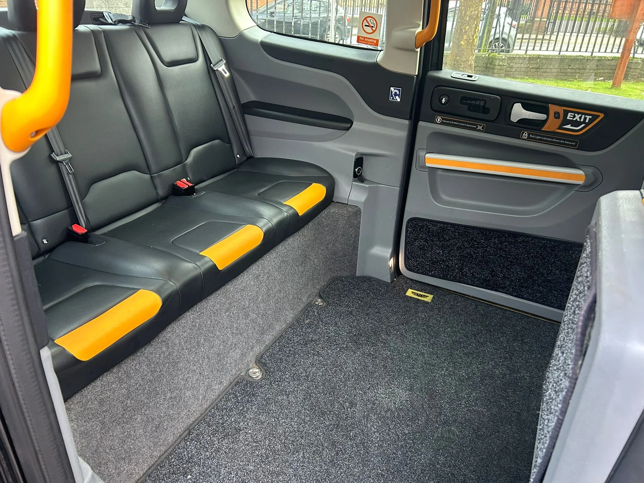 Inside of a bus showing black and yellow seats, no passengers, and safety signs on the walls.