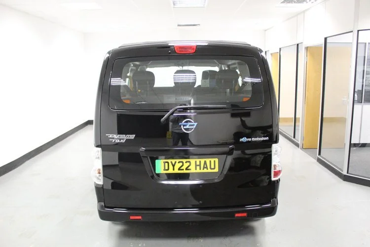 Black Opel van inside a building, showing its rear end with a yellow license plate reading 'DY22 HAU' and a reflection of the person taking the photo.