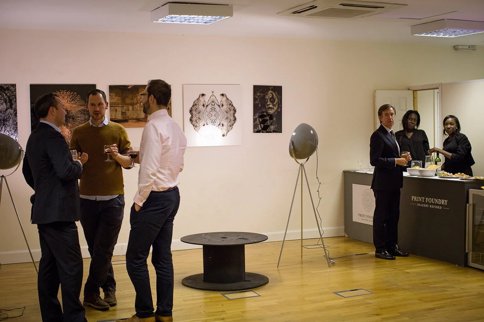 People socializing and having drinks at an art gallery and a food stand.