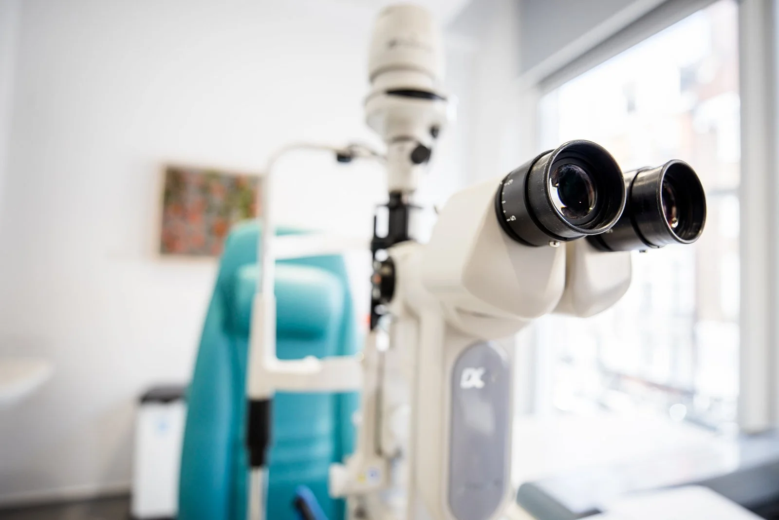 Close-up of a microscope in a medical or laboratory setting with a blurred background.