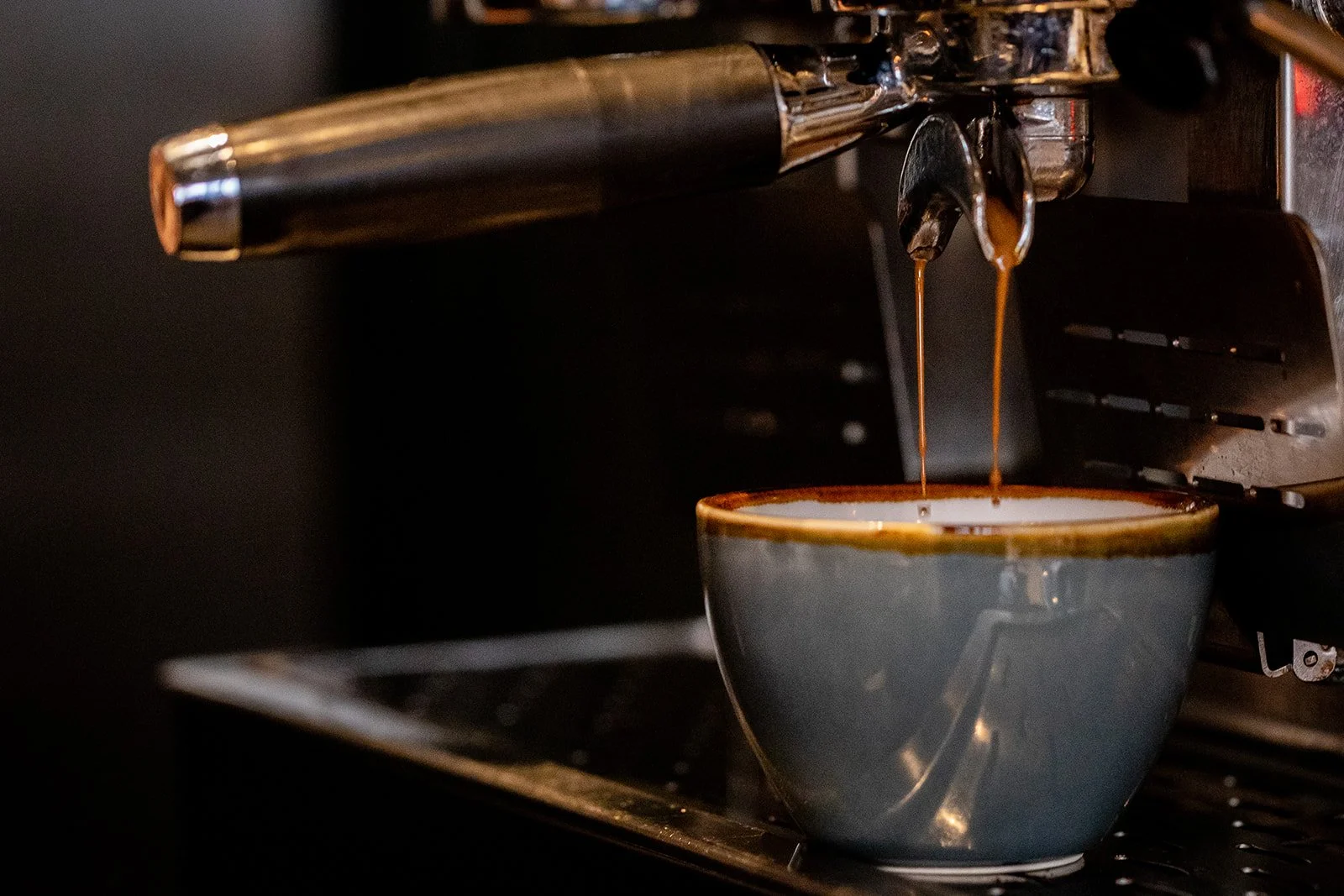 Close-up of espresso machine pouring coffee into a ceramic mug.