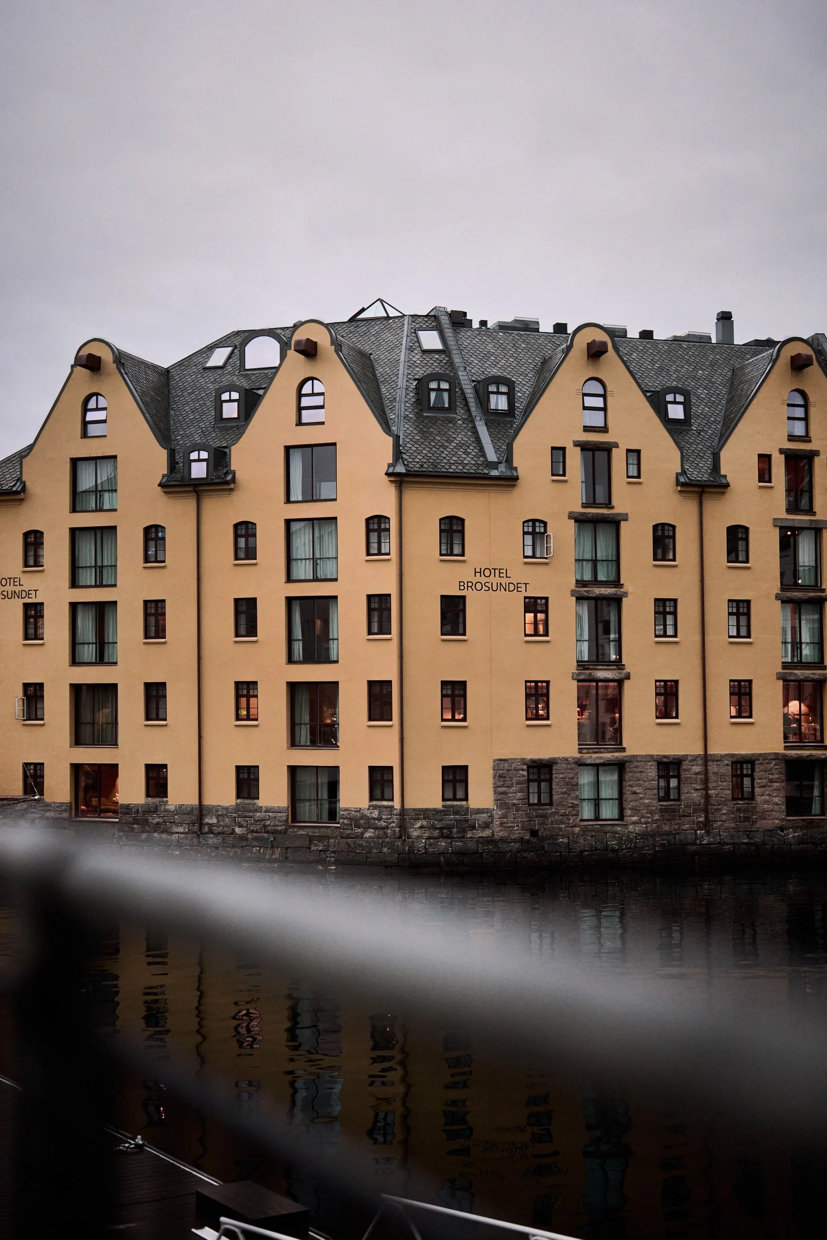 Fargerikt bygg med mange vinduer, med navnet 'HOTEL BROSUNDET', sett fra vannet foran.