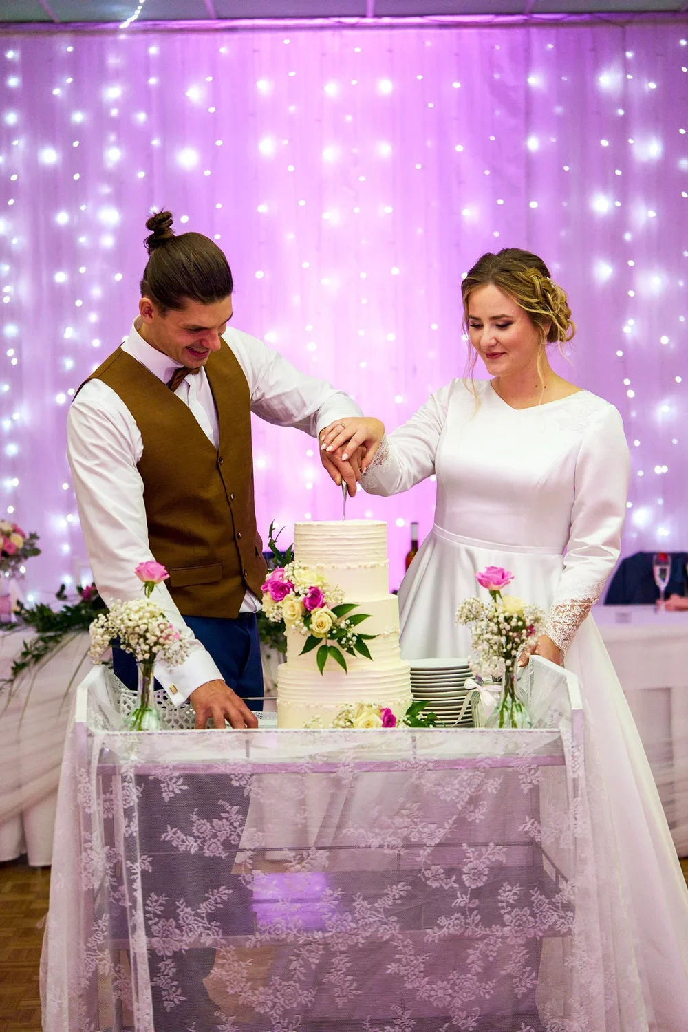 A bride and groom cutting their wedding cake together at a wedding reception.